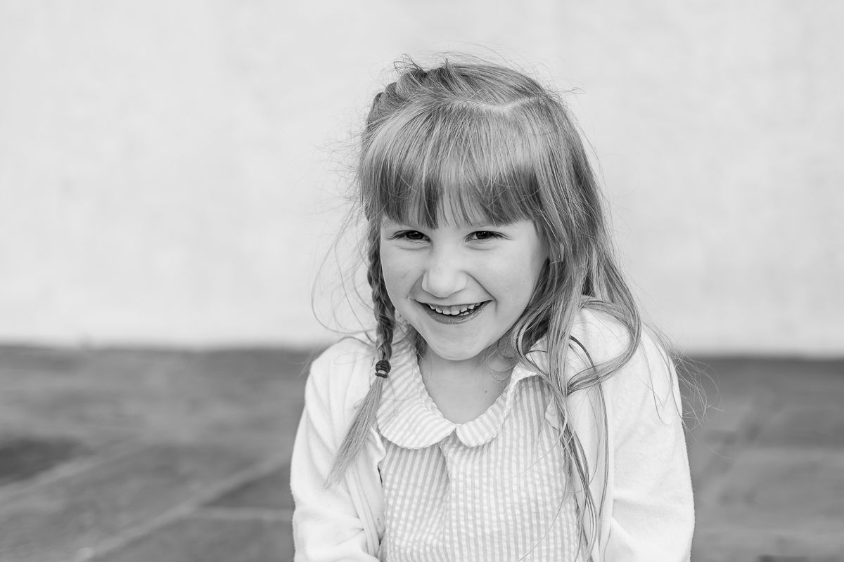 A black and white portrait of a young girl laughing at White Chimney Estates in Gap, PA during a family photography session.