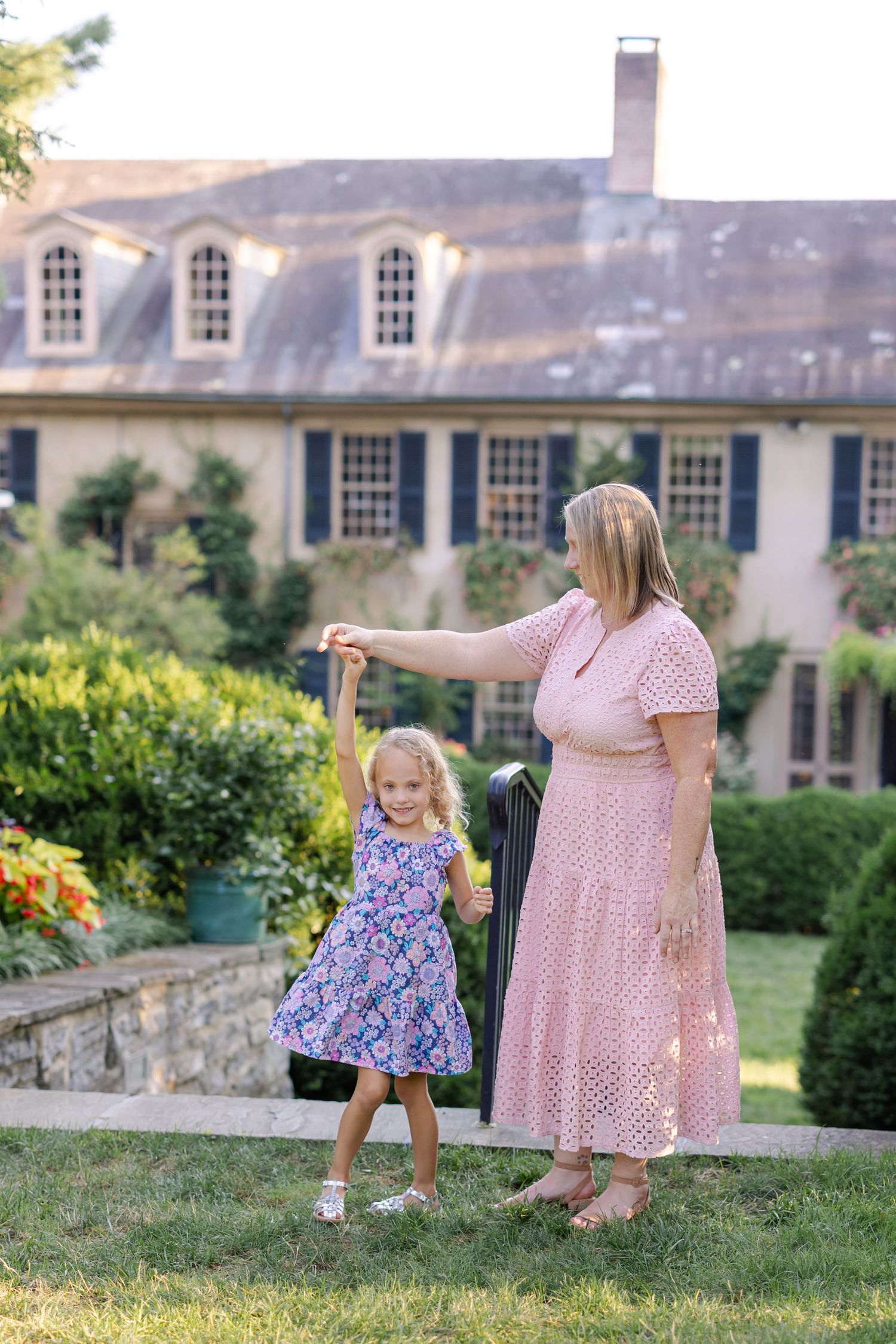 A Lancaster, PA family photographer captures a candid moment as a mother twirls her young daughter joyfully in a garden setting.