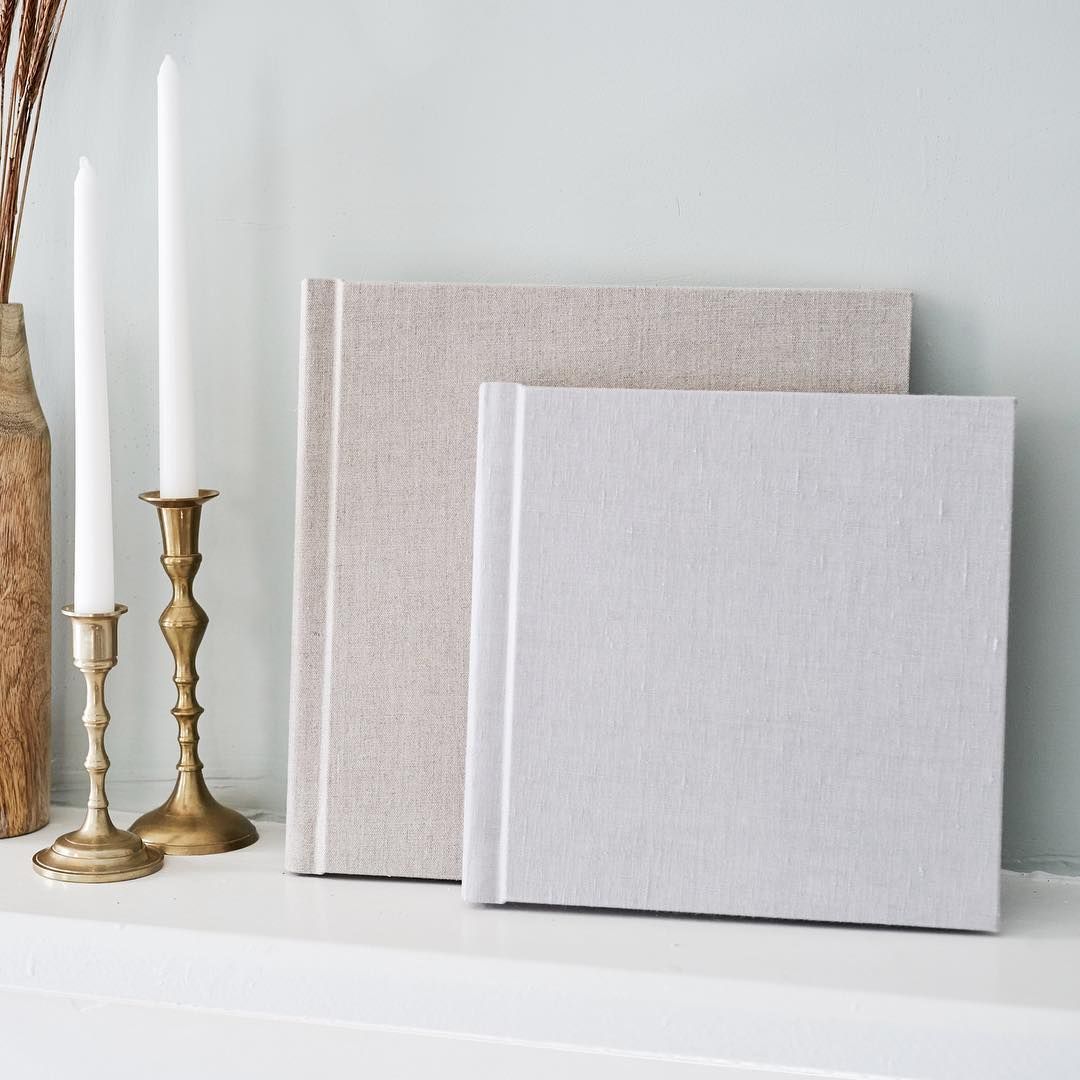 Two beautiful linen heirloom albums for senior portrait and family photography clients sit on a mantle with two candlesticks beside them.