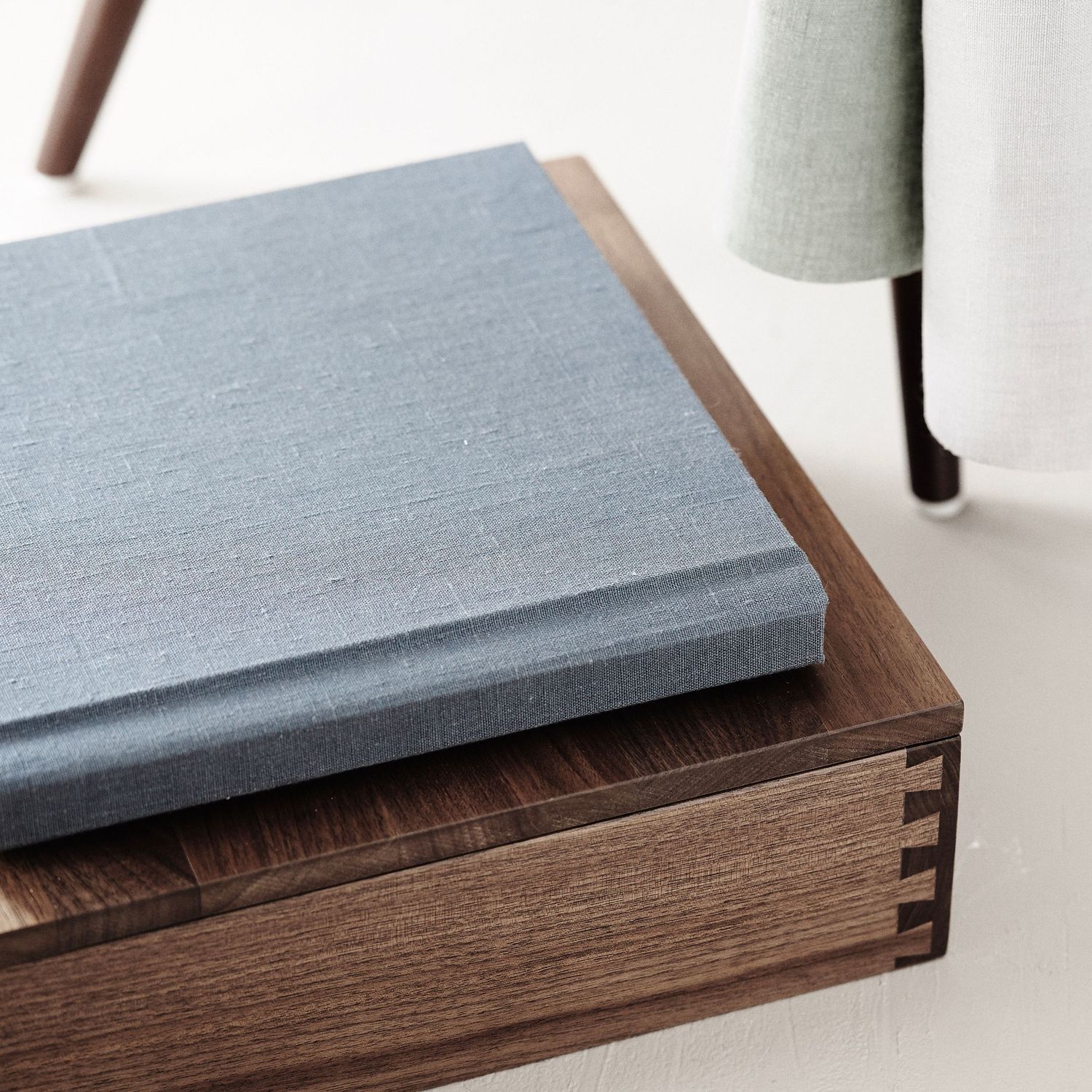A blue linen heirloom album offered by Megan Mariah Photography in Lancaster, PA sits on a walnut custom album box.