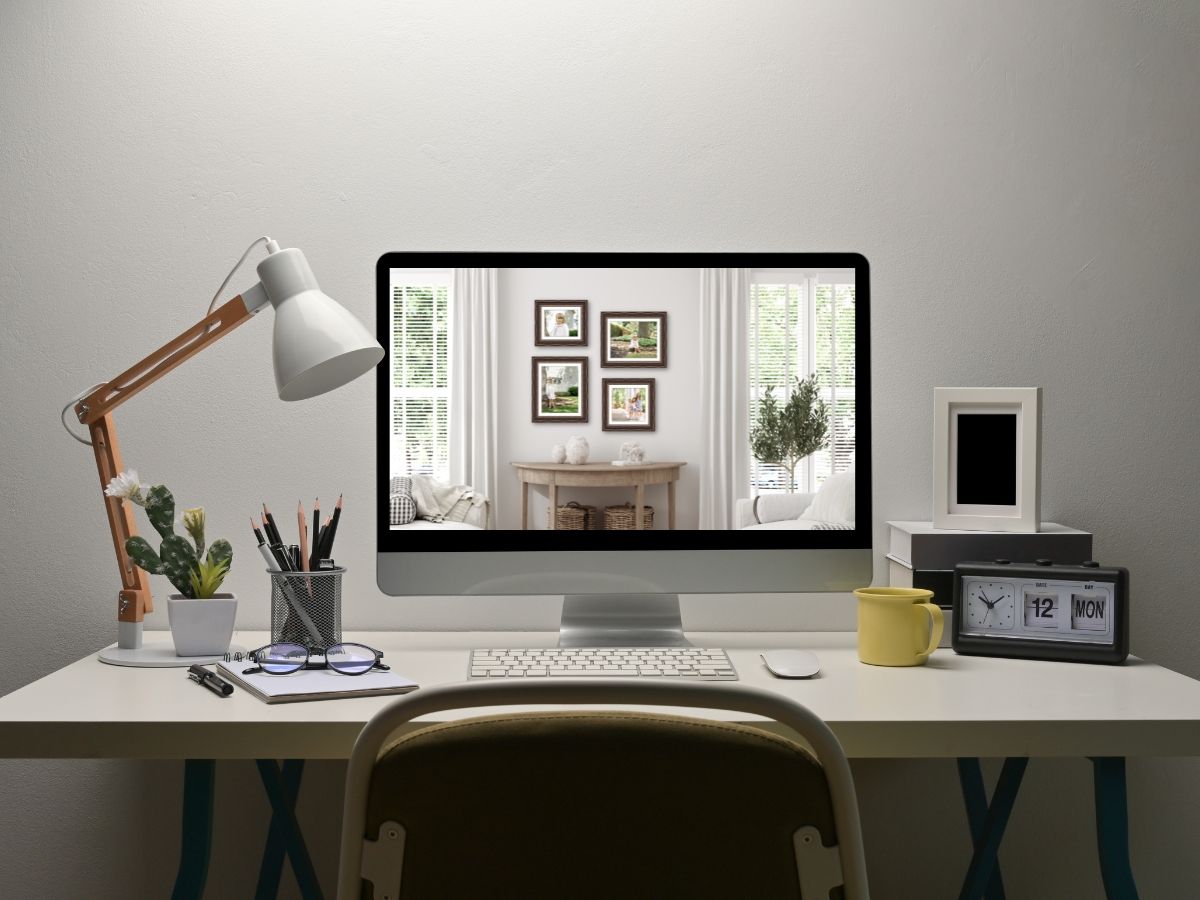 A modern home office desk with an iMac, desk lamp, cactus, pencil holder, and clock on a white surface.