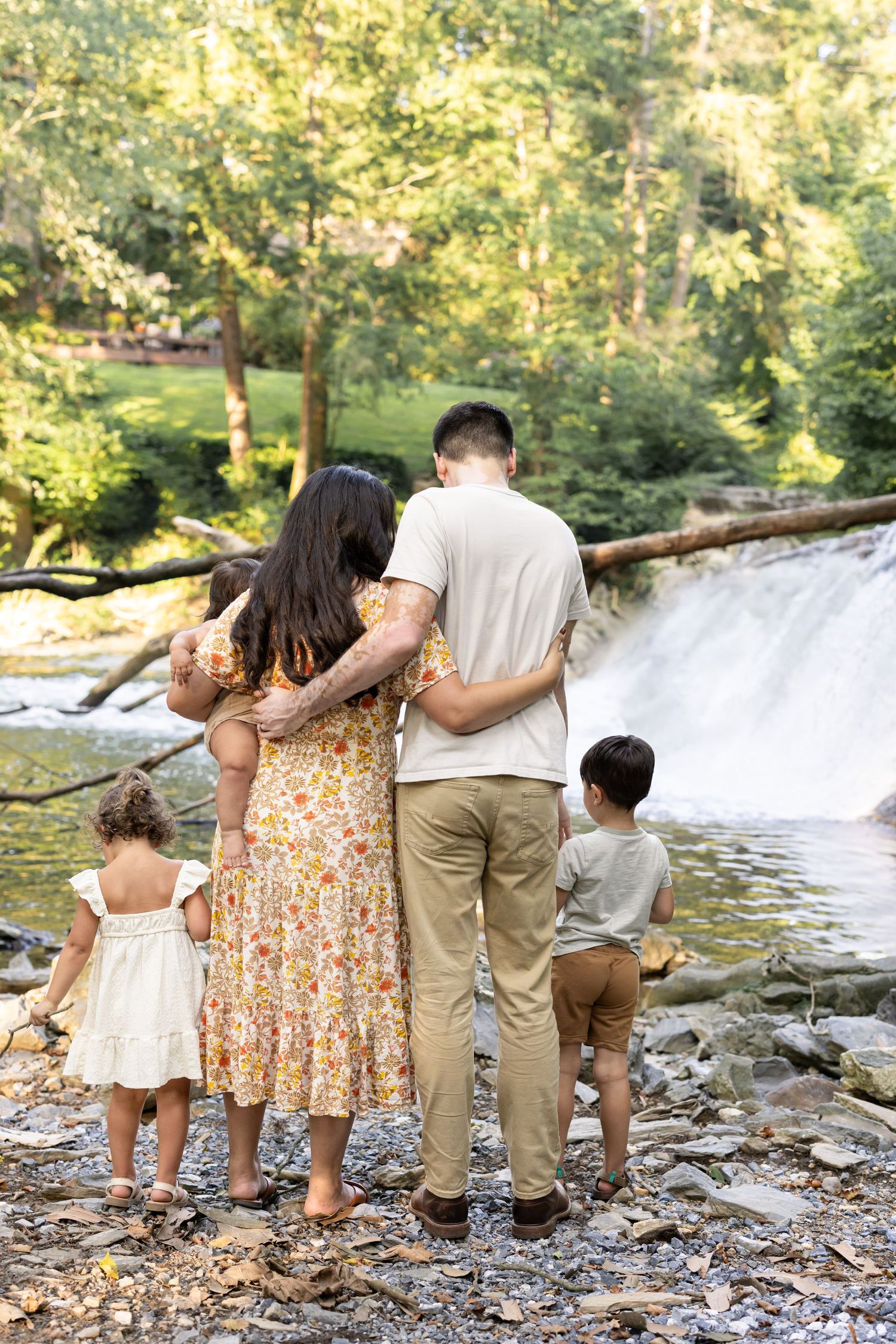 A family admires a cascading waterfall together on a sunny day in Lancaster, PA, creating peaceful outdoor family photos.