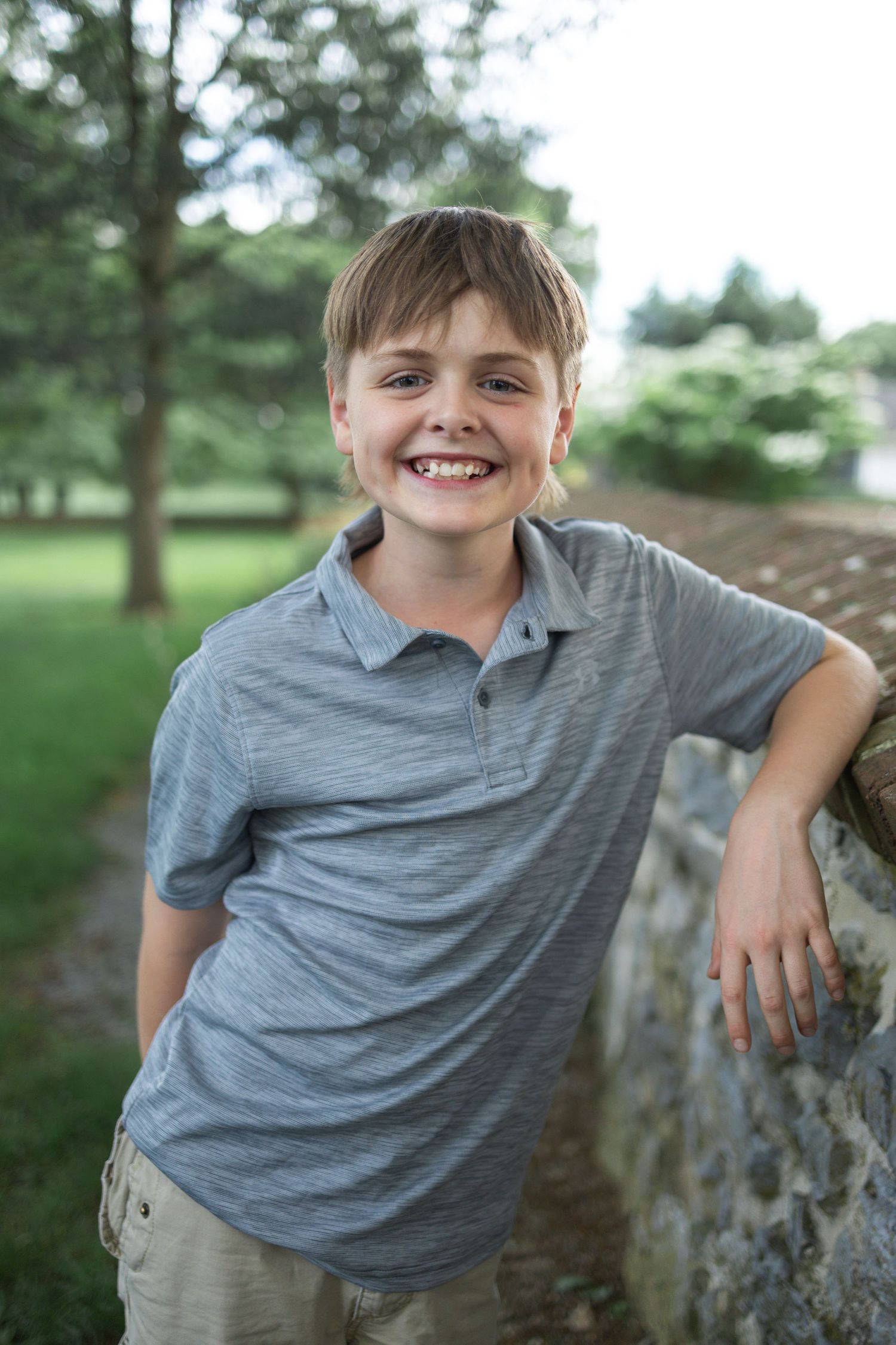 A teen boy leans on a stone wall at Donegal Presbyterian Church in Mount Joy, PA during family session with Lancaster, PA photographer