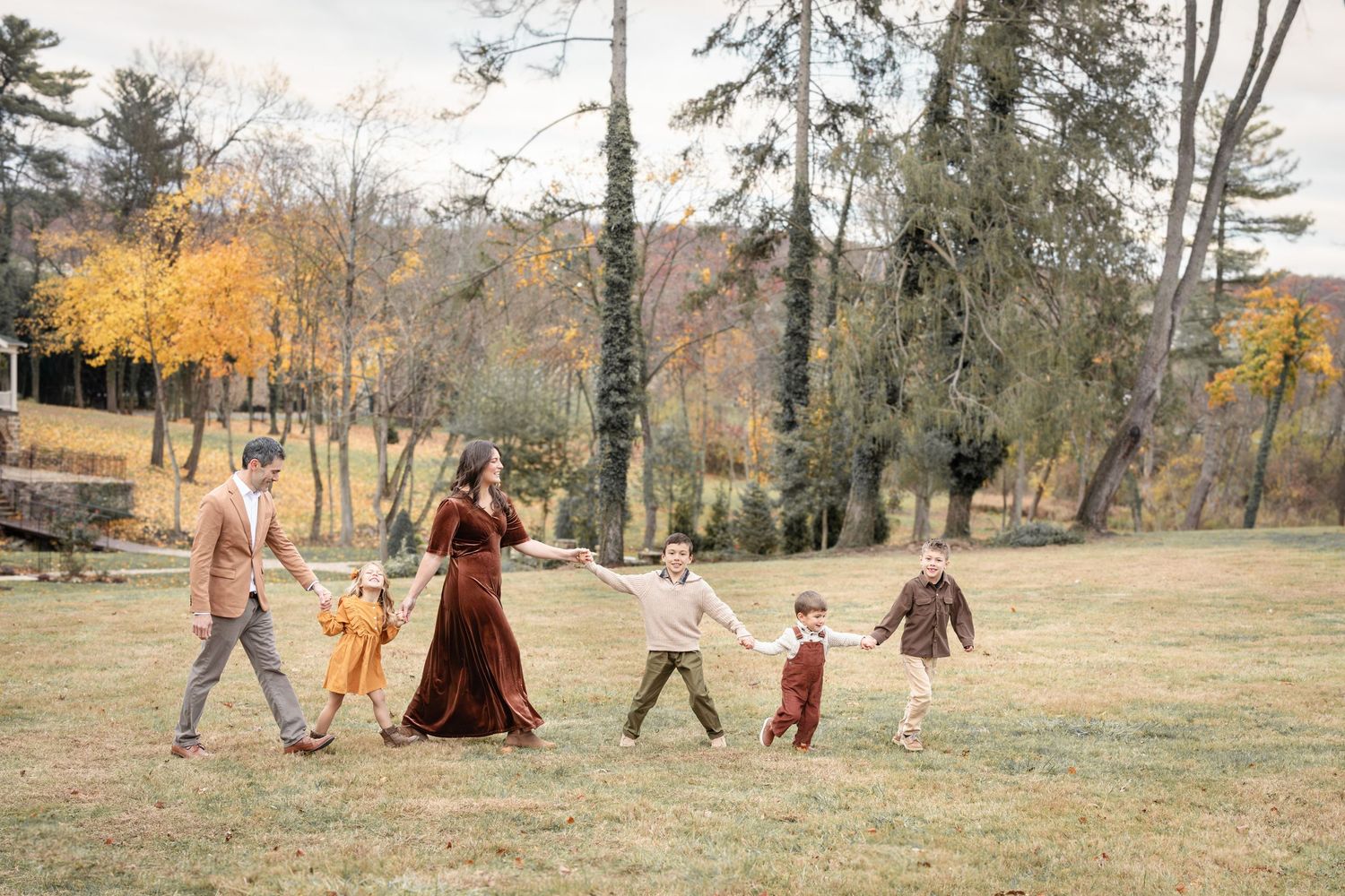 Luxury fall family portrait of a family walking across the open lawn at Historic Shady Lane in York, PA, styled beautifully and captured in