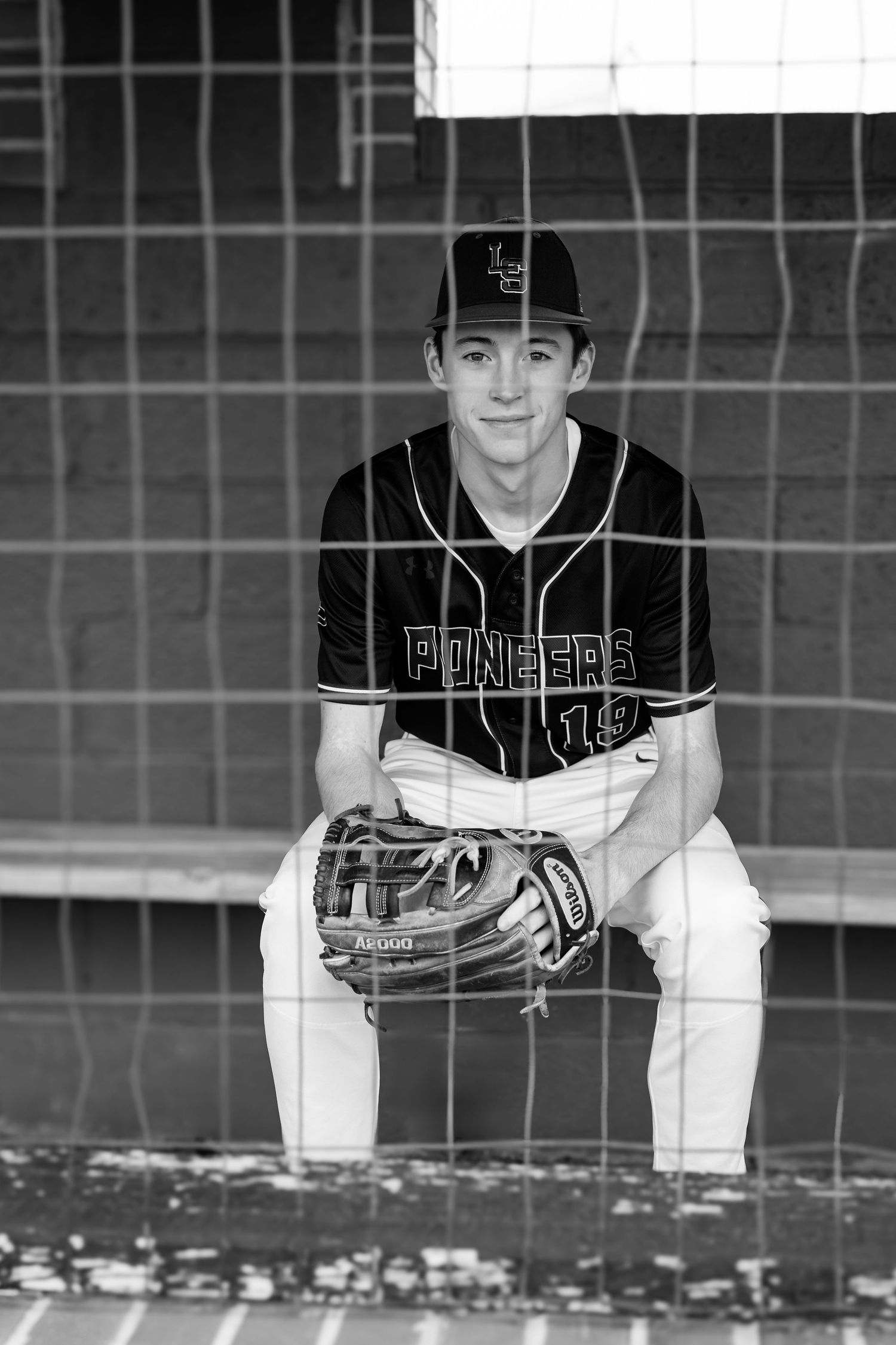 Black and white baseball photo series showing a player in uniform posing behind a chain link fence.