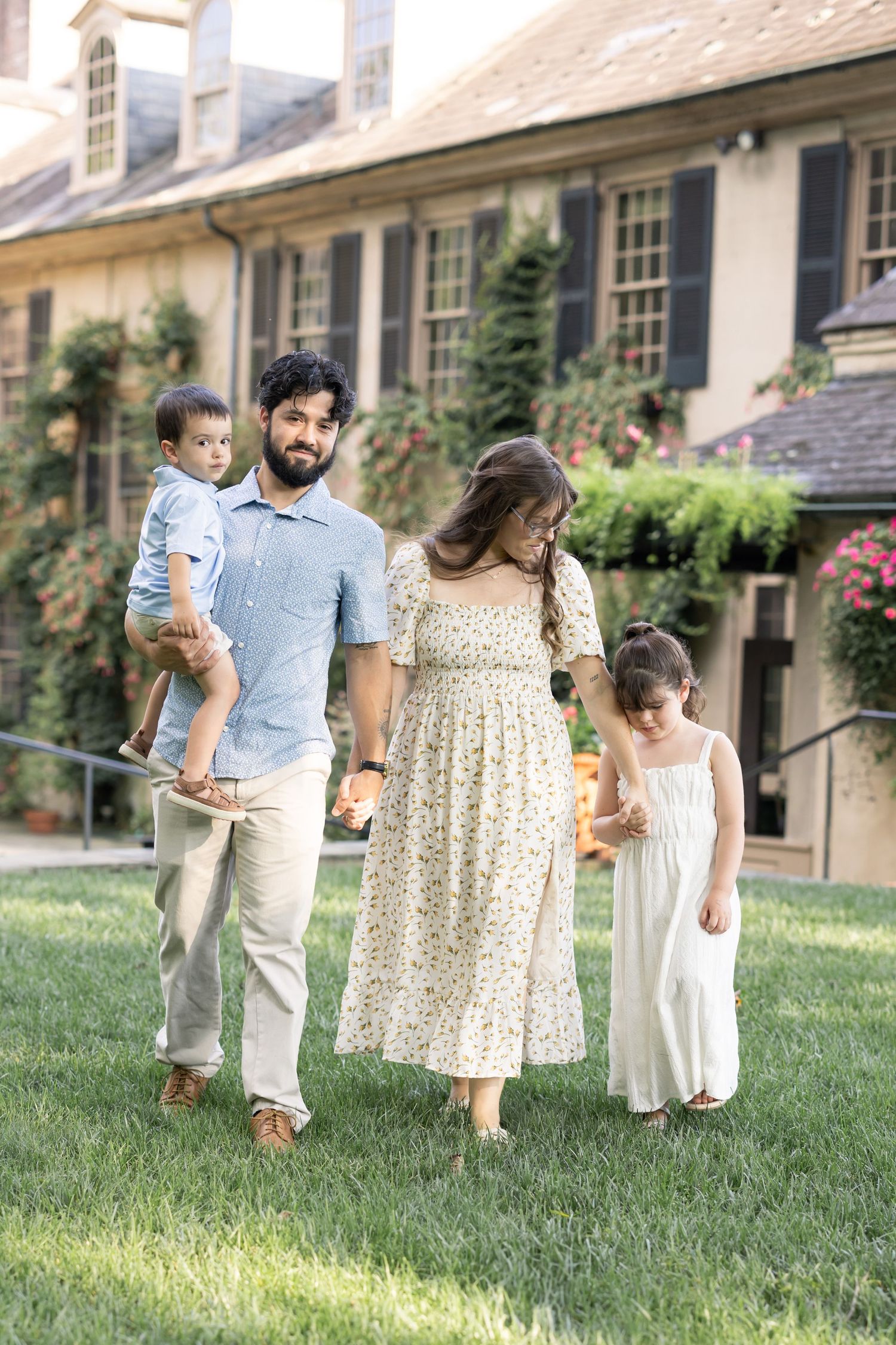 A young family walks hand in hand at Conestoga House and Gardens in Lancaster PA during a candid family photo session.