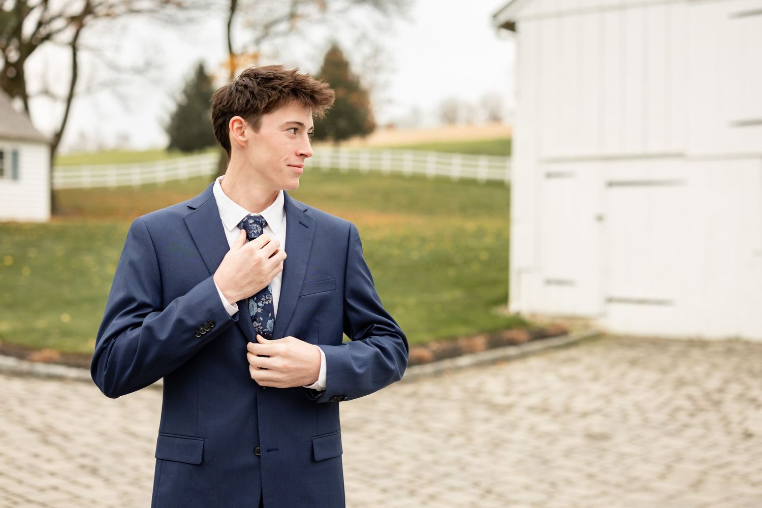 High school senior boy photographed in a luxury venue setting, wearing a modern blue suit and tie | refined senior portrait by Megan Mariah
