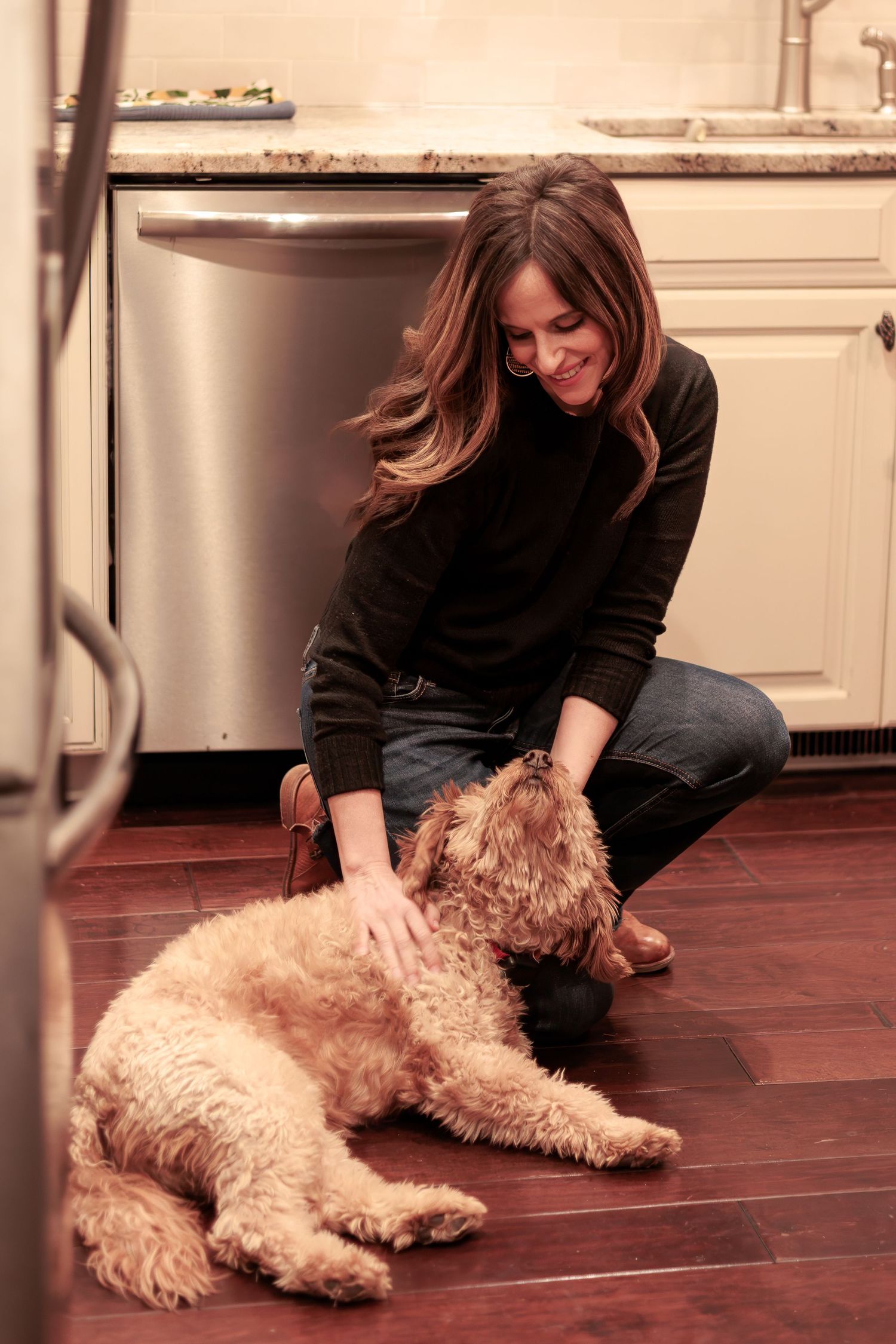 Megan Mariah, a senior and family portrait photographer in Lancaster, PA plays with her mini-goldendoodle dog in her home.