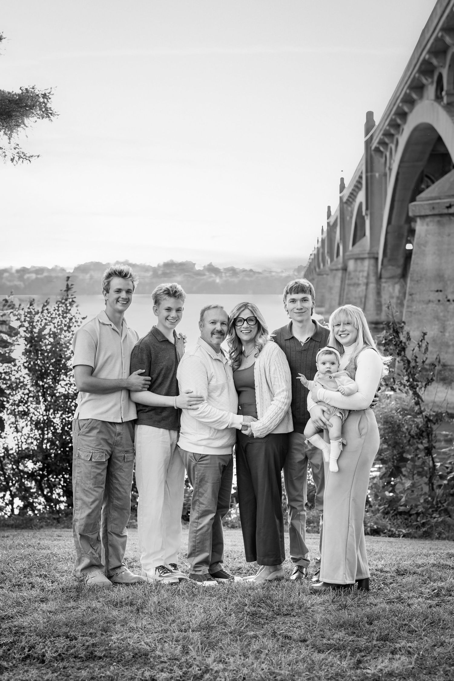 A black and white photograph of a family standing outdoors in a garden setting.