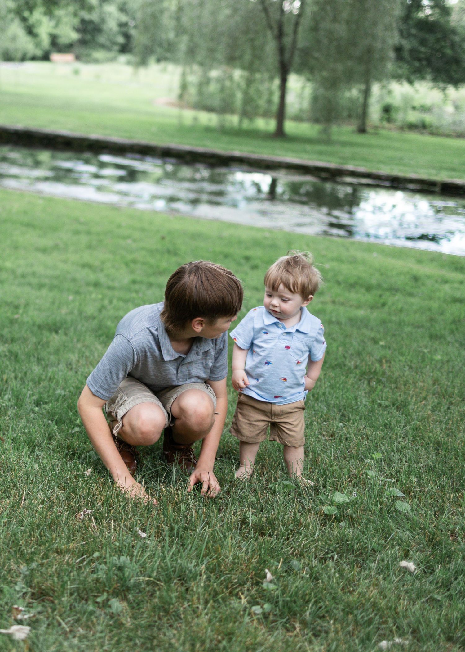 Two brothers play in grass at Donegal Presbyterian Church in Mount Joy, PA during family session with Lancaster, PA photographer