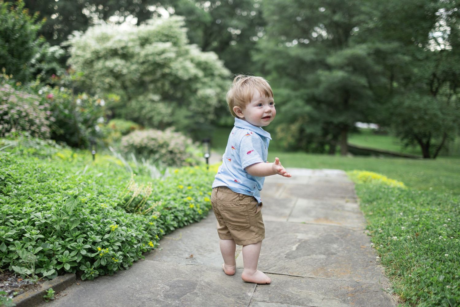 Toddler boy stands on stone path at Donegal Presbyterian Church in Mount Joy, PA during family session with Lancaster, PA photographer.