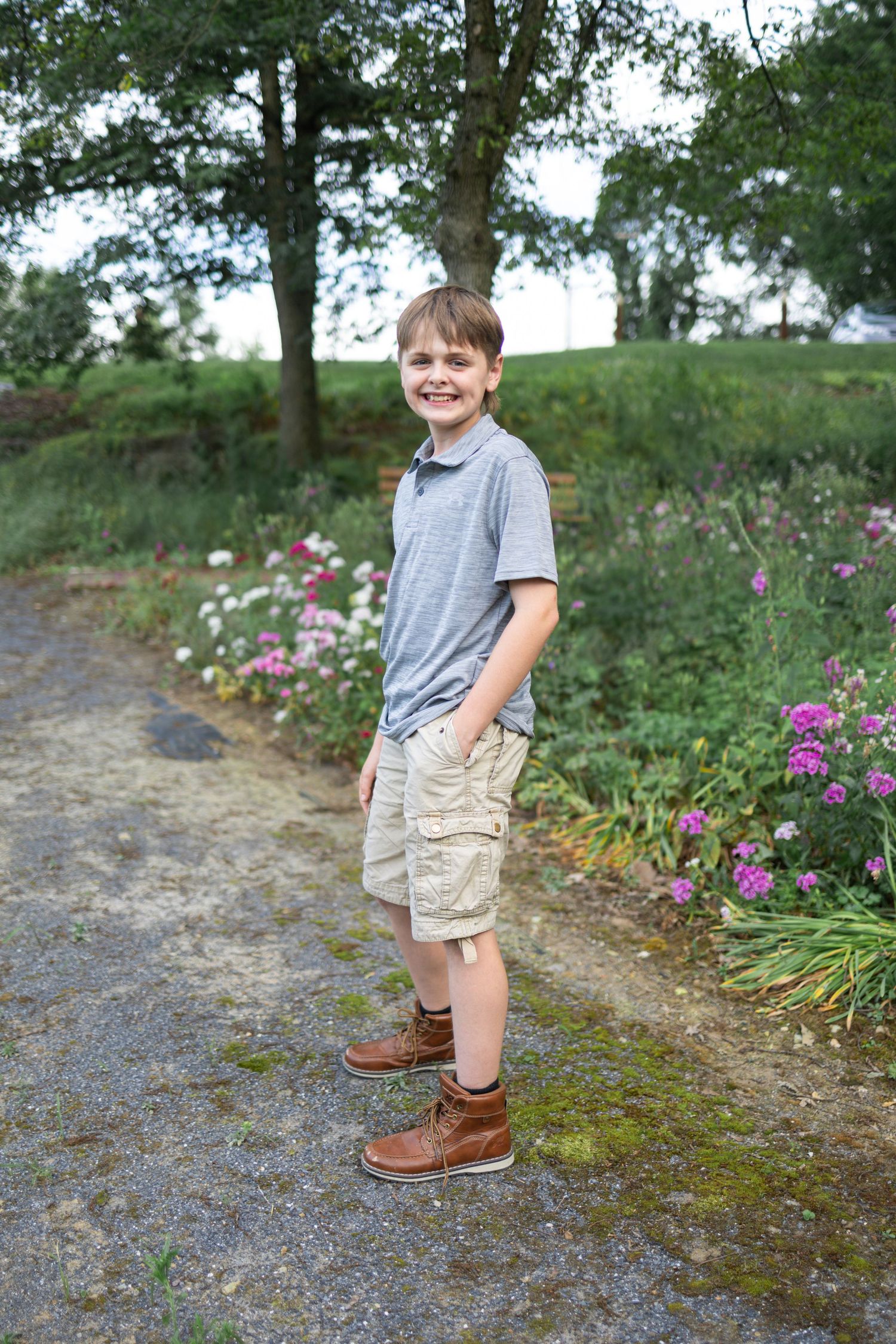 teen boy poses by wildflowers at Donegal Presbyterian Church in Mount Joy, PA during family session with Lancaster, PA photographer