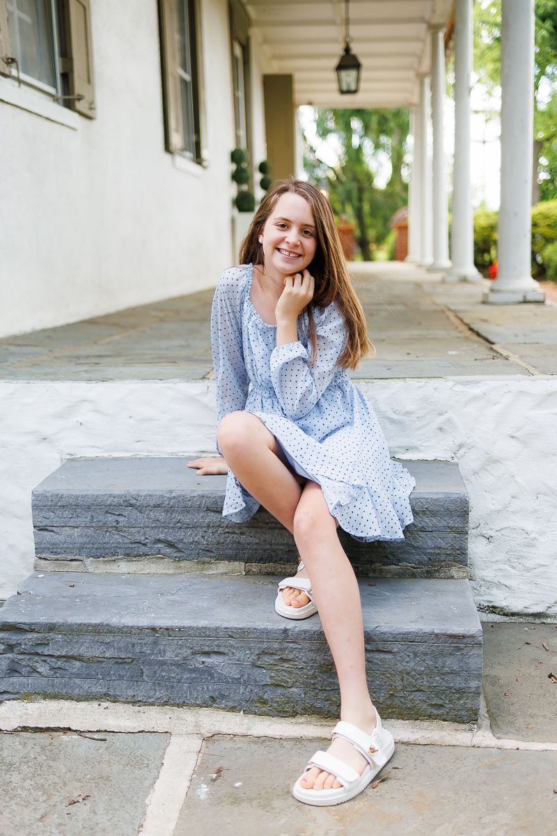Beautiful teen girl sitting on steps at White Chimneys Estate in Gap, PA during a family milestone session with Lancaster, PA photographer.