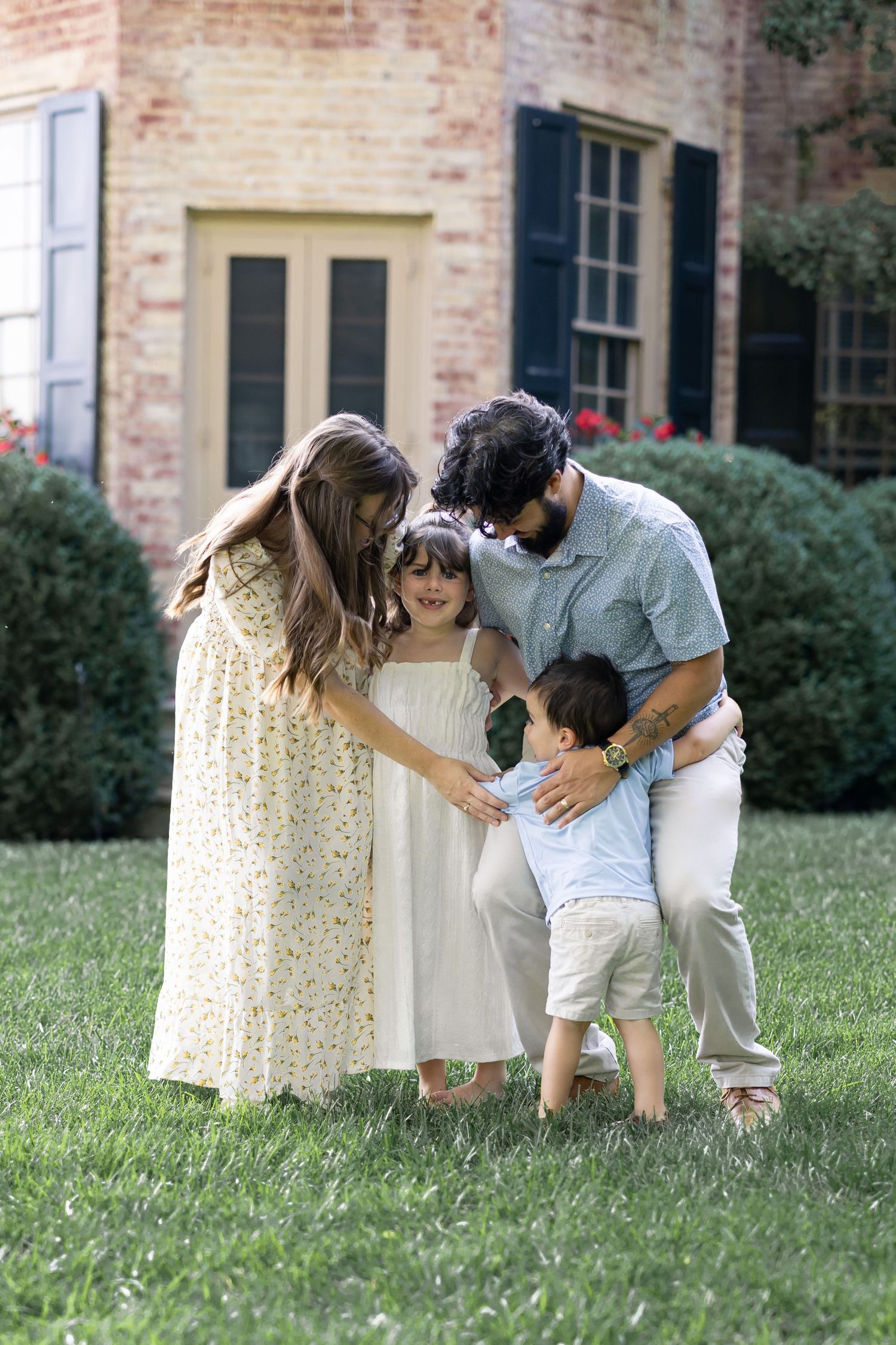 High-end portrait of a mother and father embracing their young daughter and son in a candid moment with Lancaster, PA family photographer.