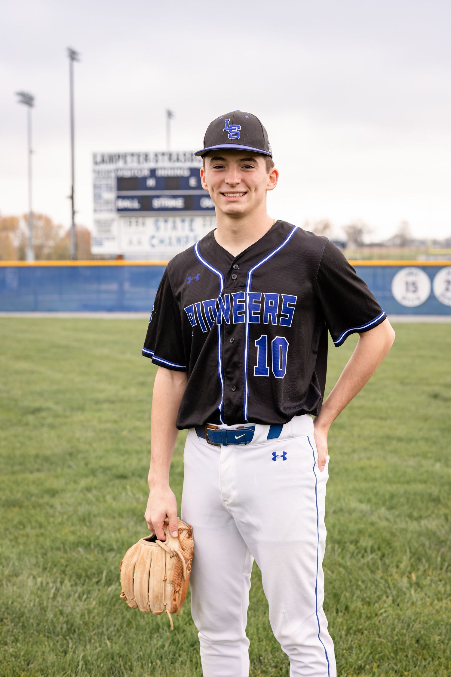 A posed portrait of a high school senior boy in baseball uniform on his home field in Lancaster, PA | luxury senior photography in Lancaster