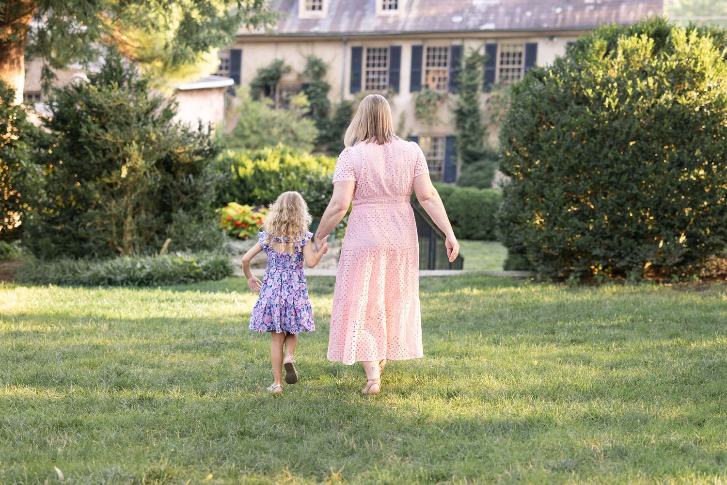 A mother and daughter walking towards a grand house hand in hand, image by Megan Mariah Photography, Lancaster, PA.