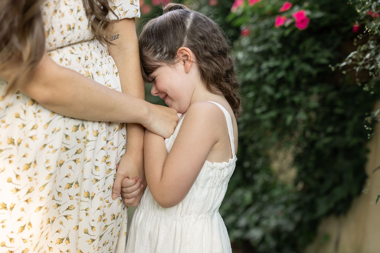 A young mother and daughter in long, flowy dresses share a candid embrace during family photos in Lancaster, PA.
