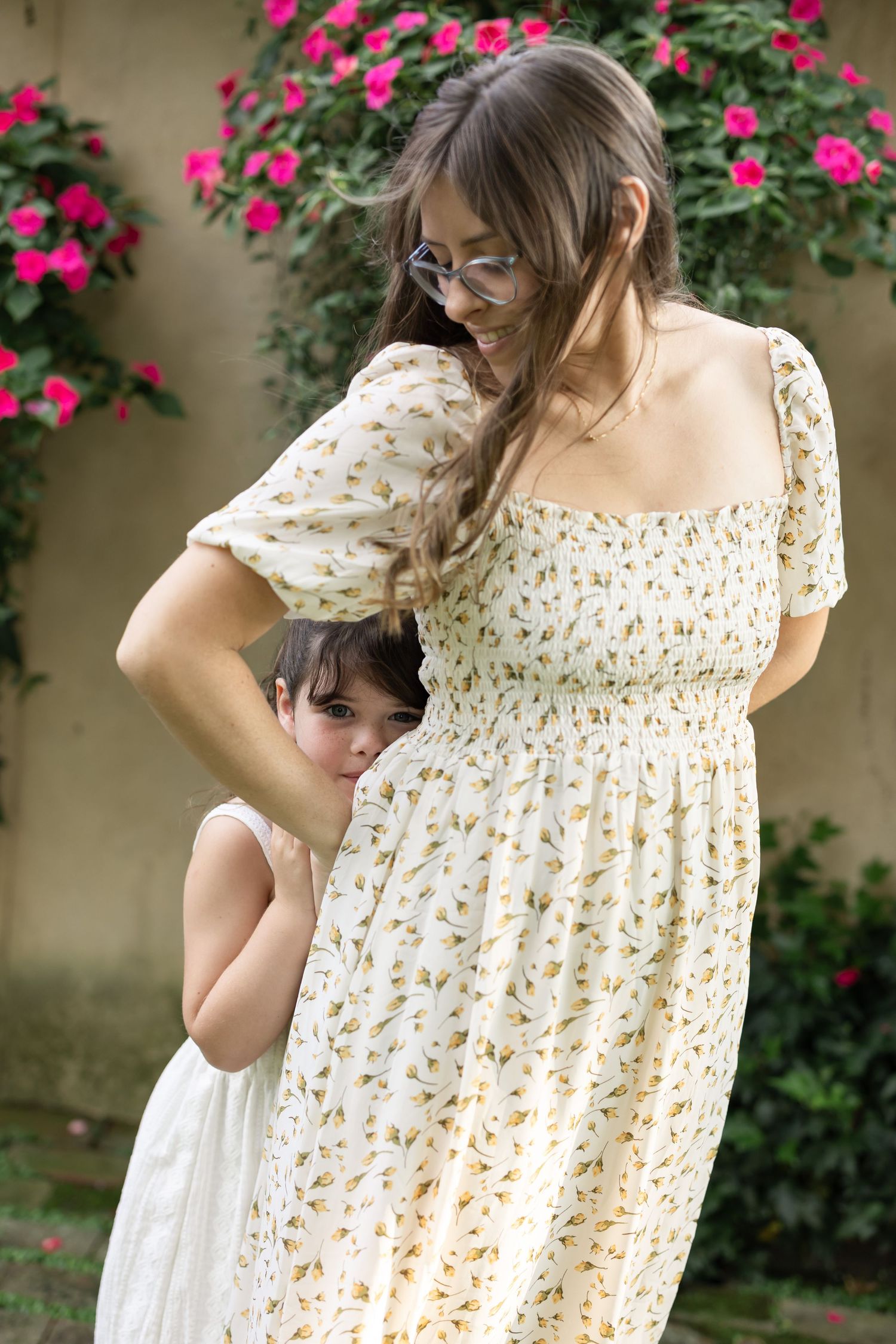 A young girl peers out from behind her mother's flowy dress during a candid and elevated family photo session in Lancaster, PA.