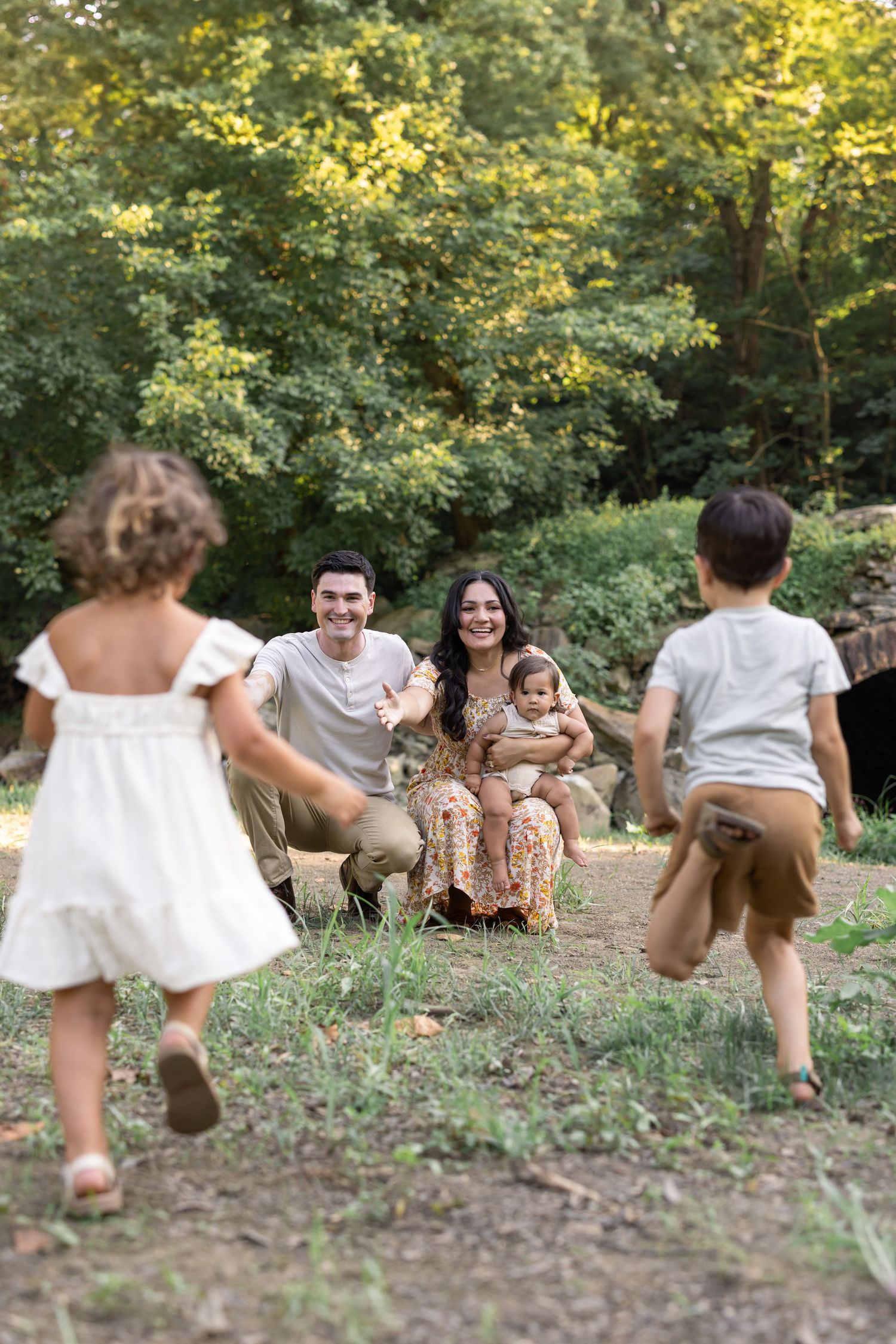 A candid family photo of two children running into the arms of their mother and father during a family photo session in Lancaster, PA.