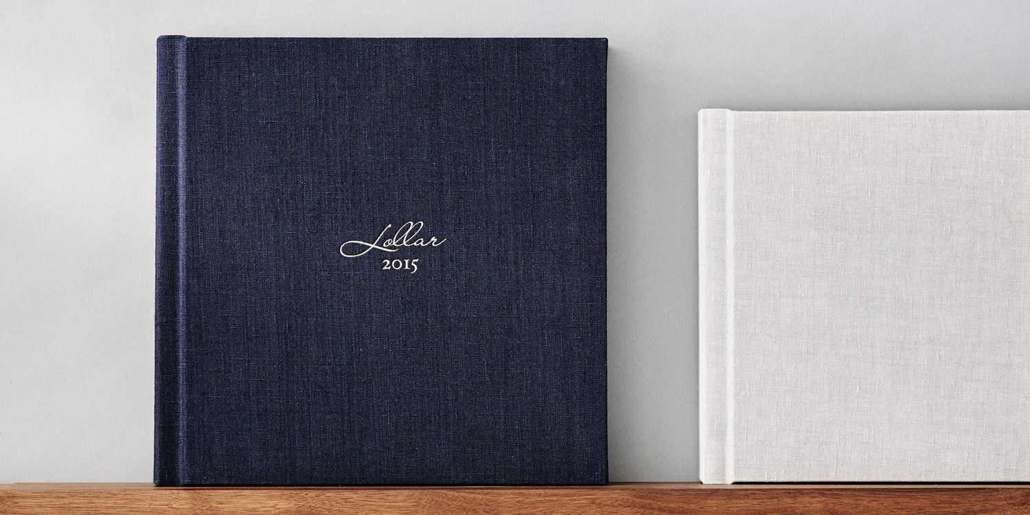Professional navy blue linen photo album collection displayed on wooden surface.