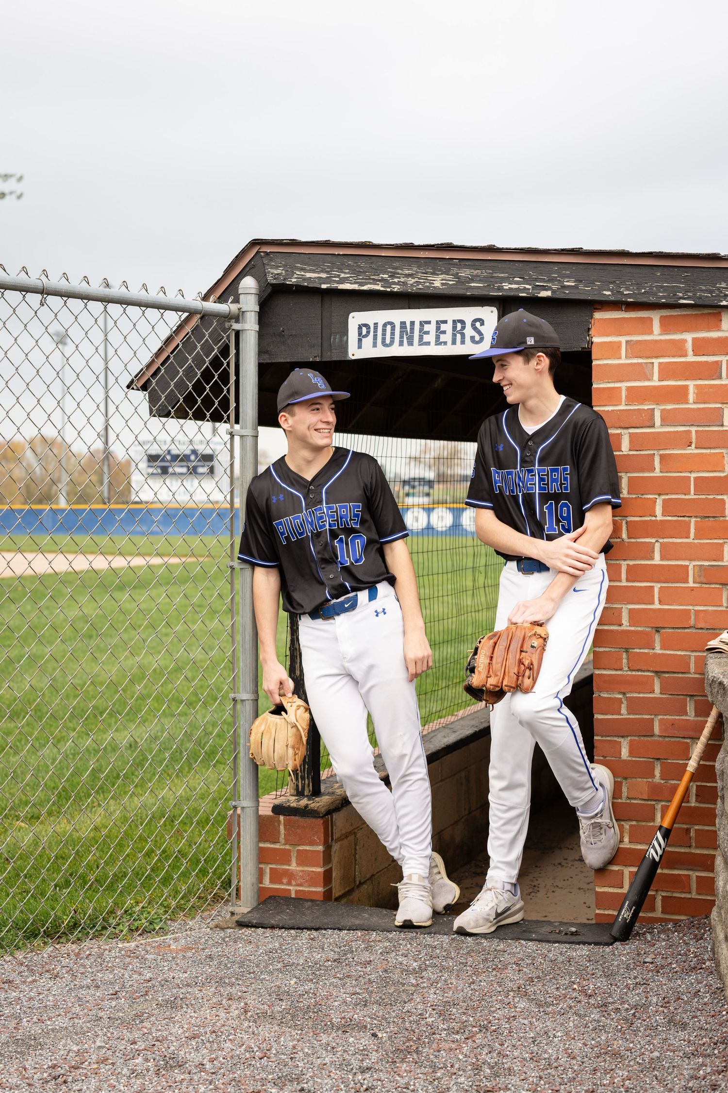 Senior pictures in Lancaster, PA | Two brothers candidly chatting by the baseball field for sports portraits