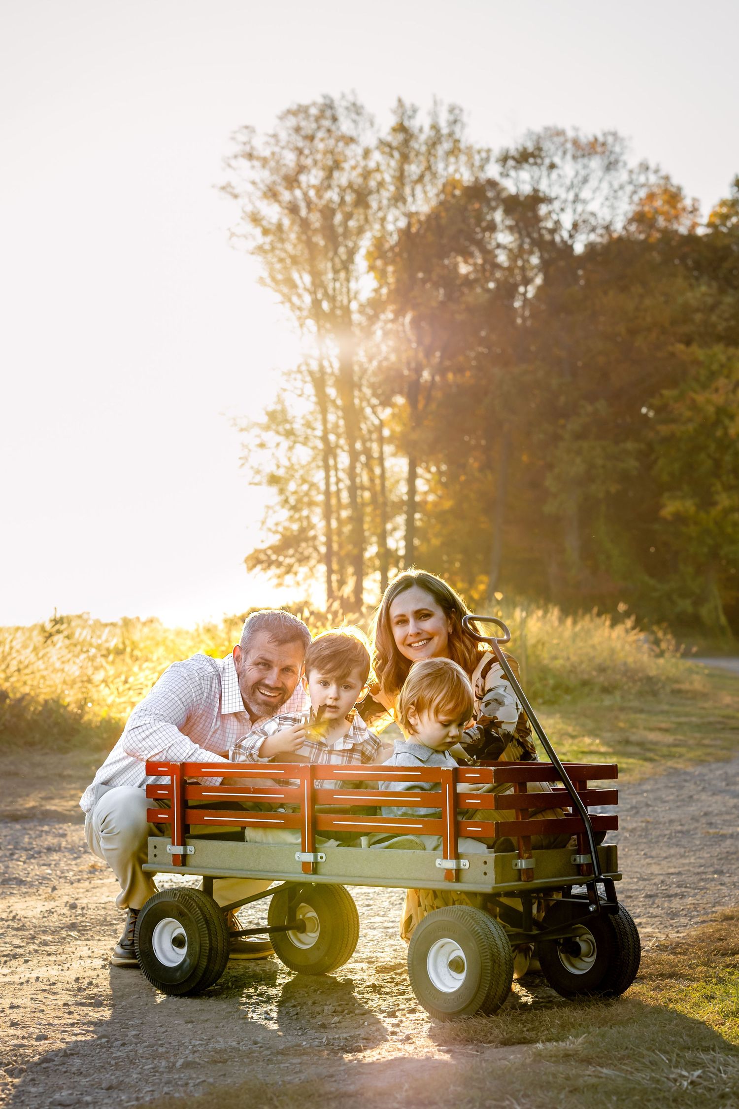 A family enjoying a sunset moment together while sitting in a wooden wagon outdoors.