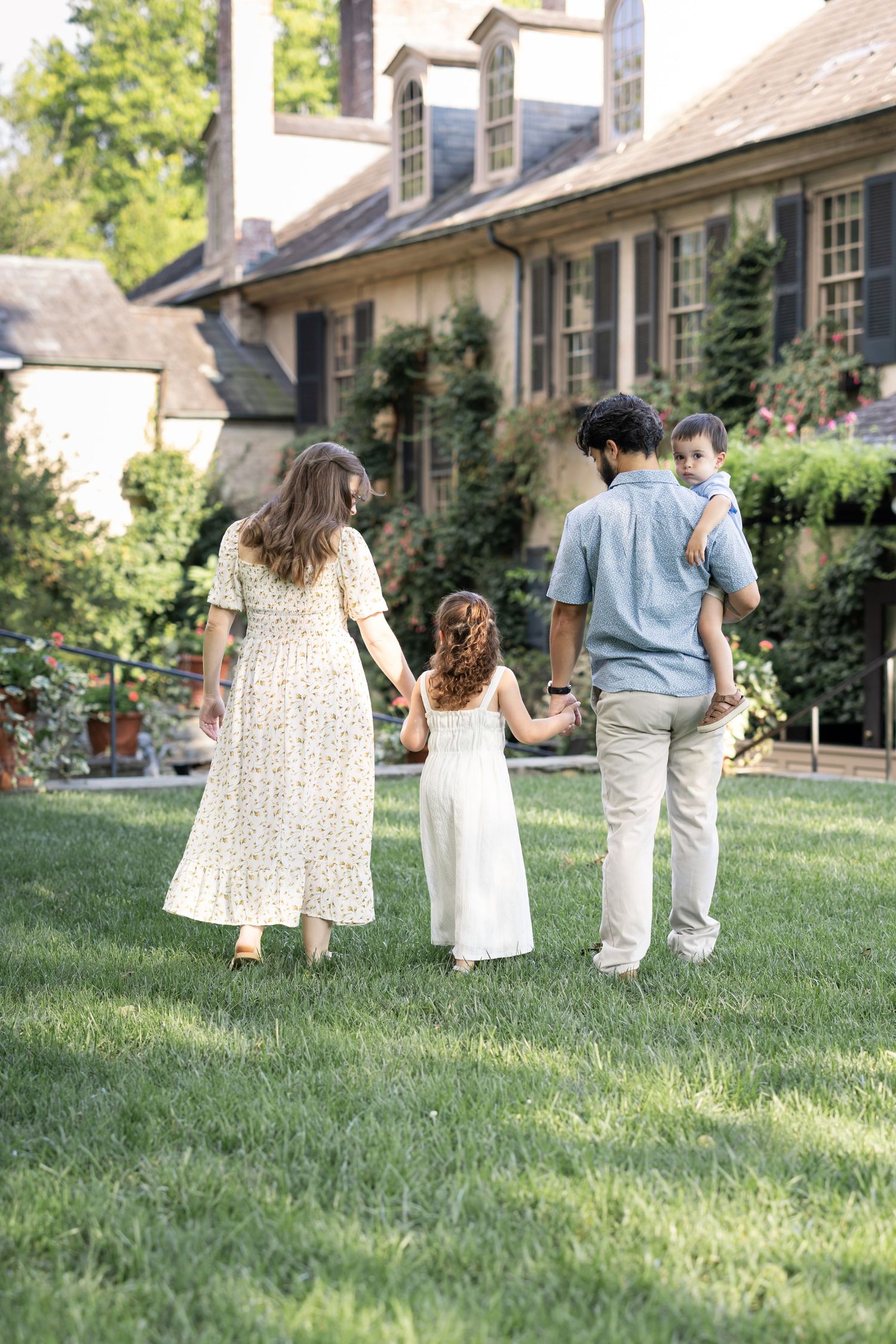 A luxury family photography session in Lancaster, PA features a young family of four walking leisurely through a lush, vibrant garden.