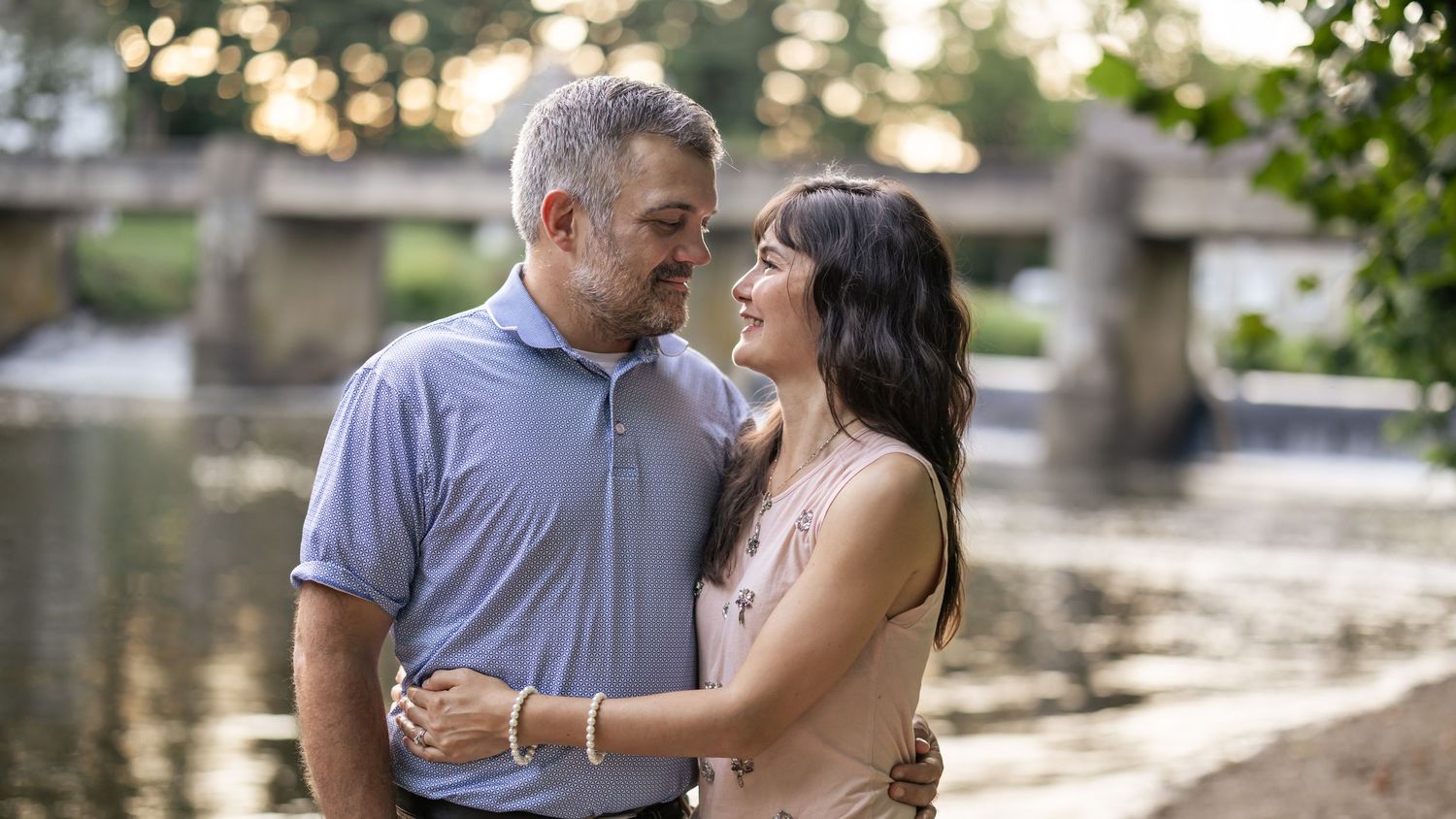Romantic couple embraces and laughs together while strolling through a garden pathway on a sunny afternoon.