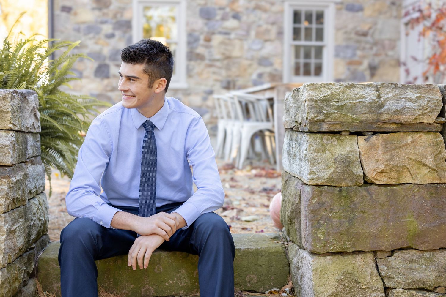 Professional portrait session by weathered stone wall during golden hour.