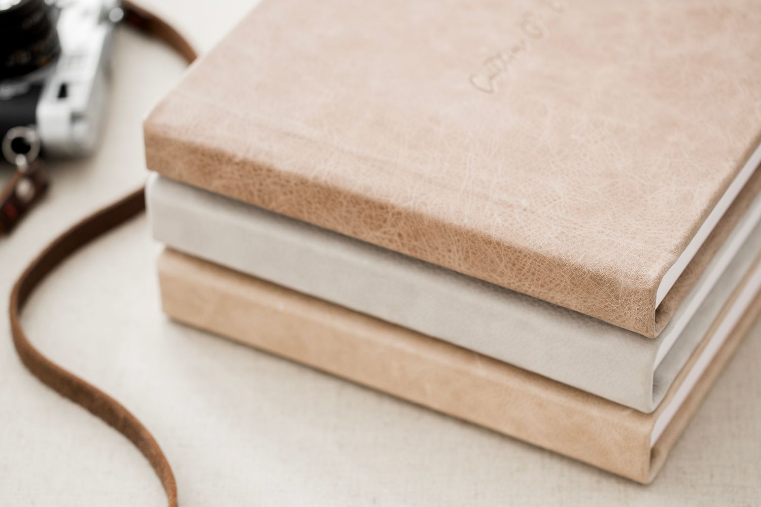 A stack of three beautiful leather senior portrait and family heirloom albums in light brown, dark brown, and beige, sold in Lancaster, PA.