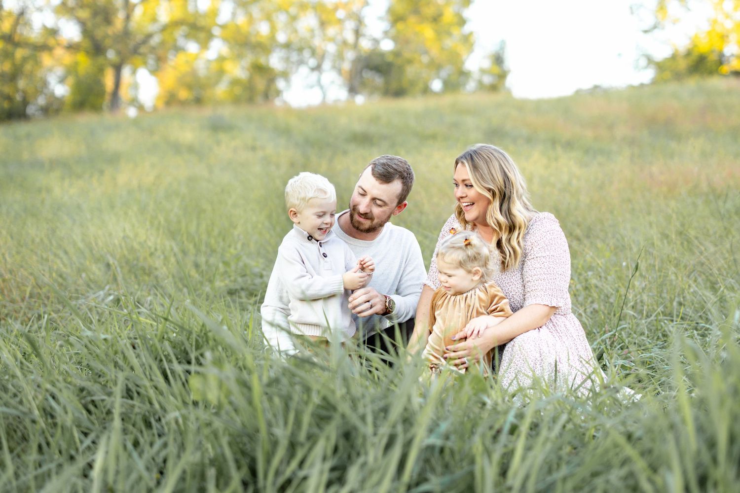 A luxury family portrait in Lancaster, PA features a young family sharing a heartfelt moment in a lush, grassy field.