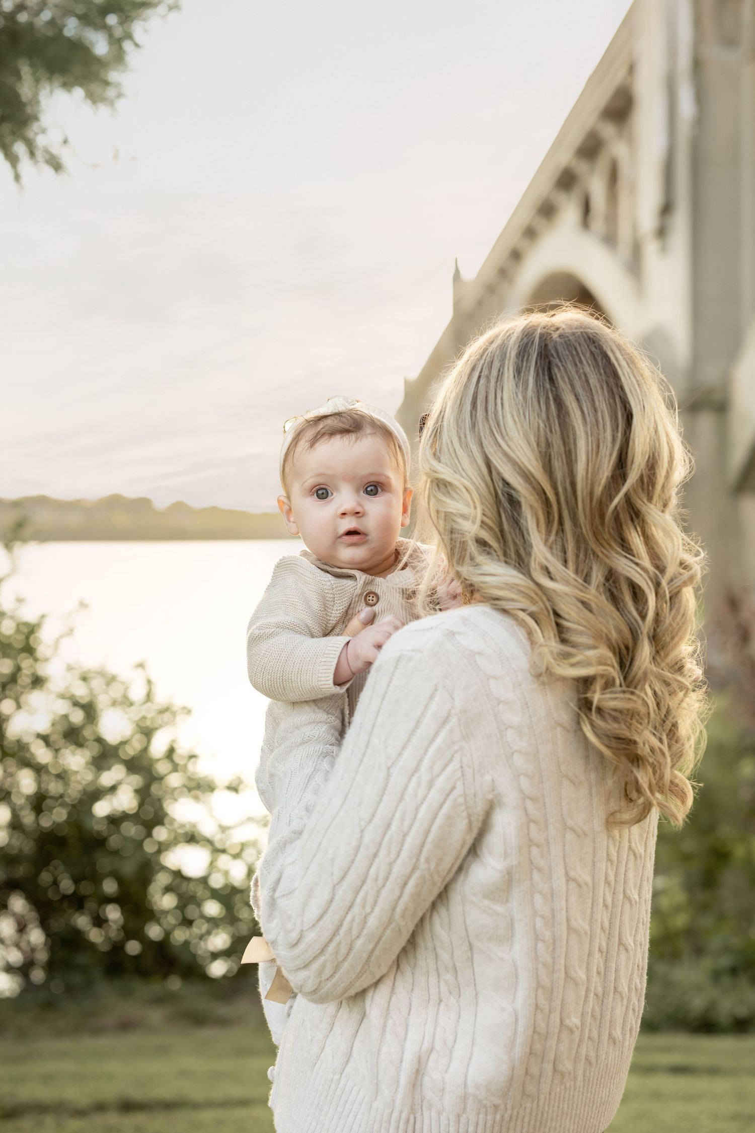 Elegant portrait of a woman with flowing hair holding her baby by the historic bridge in York, PA, captured in a refined, luxury fine art st