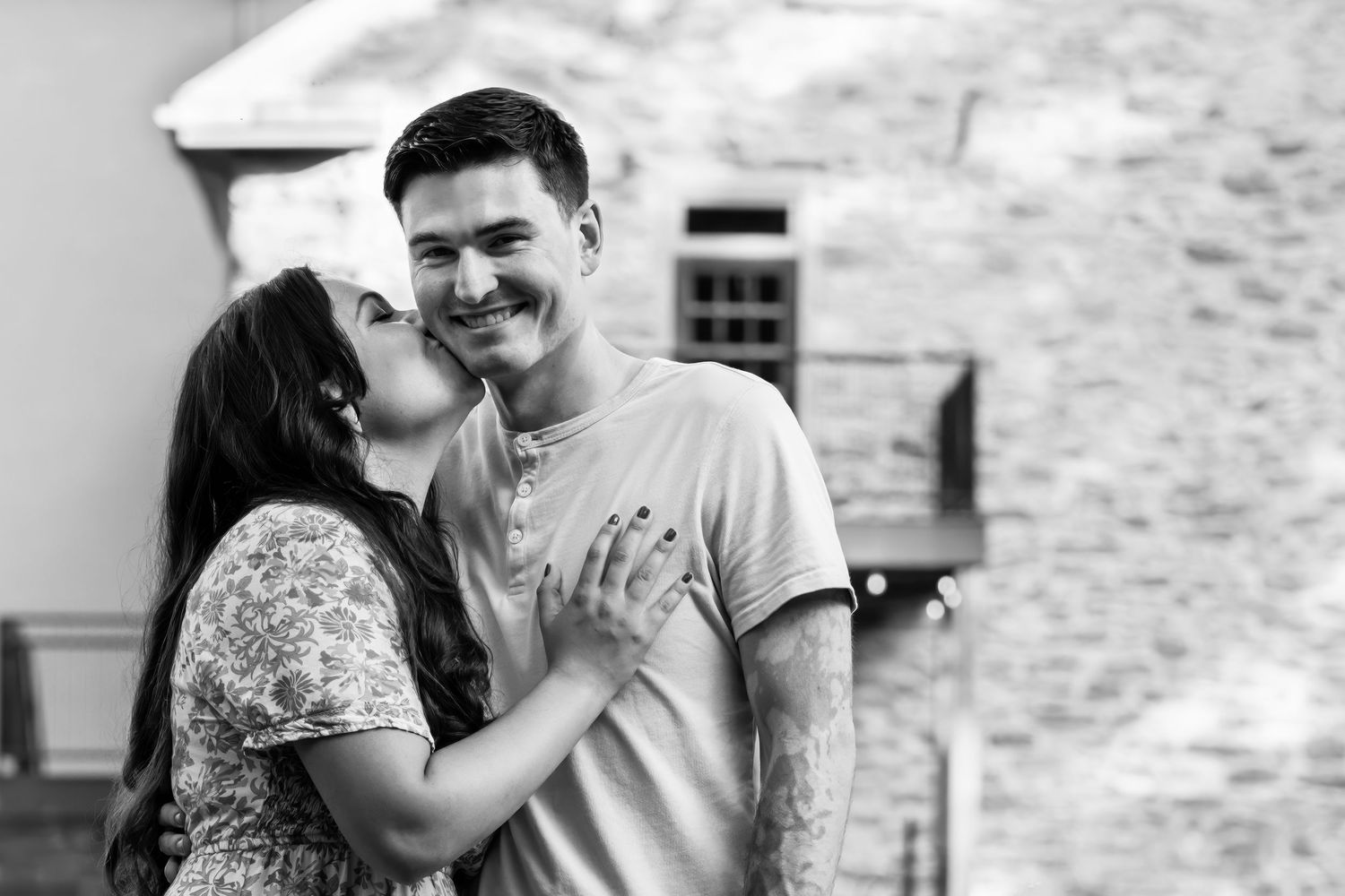 A couple shares intimate moments in black and white photographs during an outdoor engagement photoshoot.