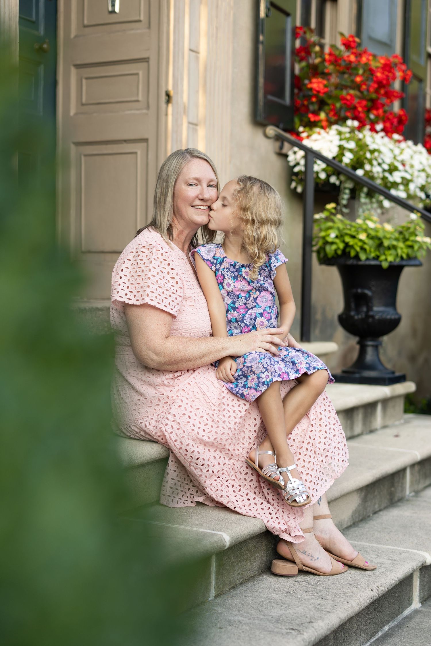 A mother sits with her young daughter on stone steps in front of the Conestoga House in Lancaster, PA. Image by Megan Mariah Photography.