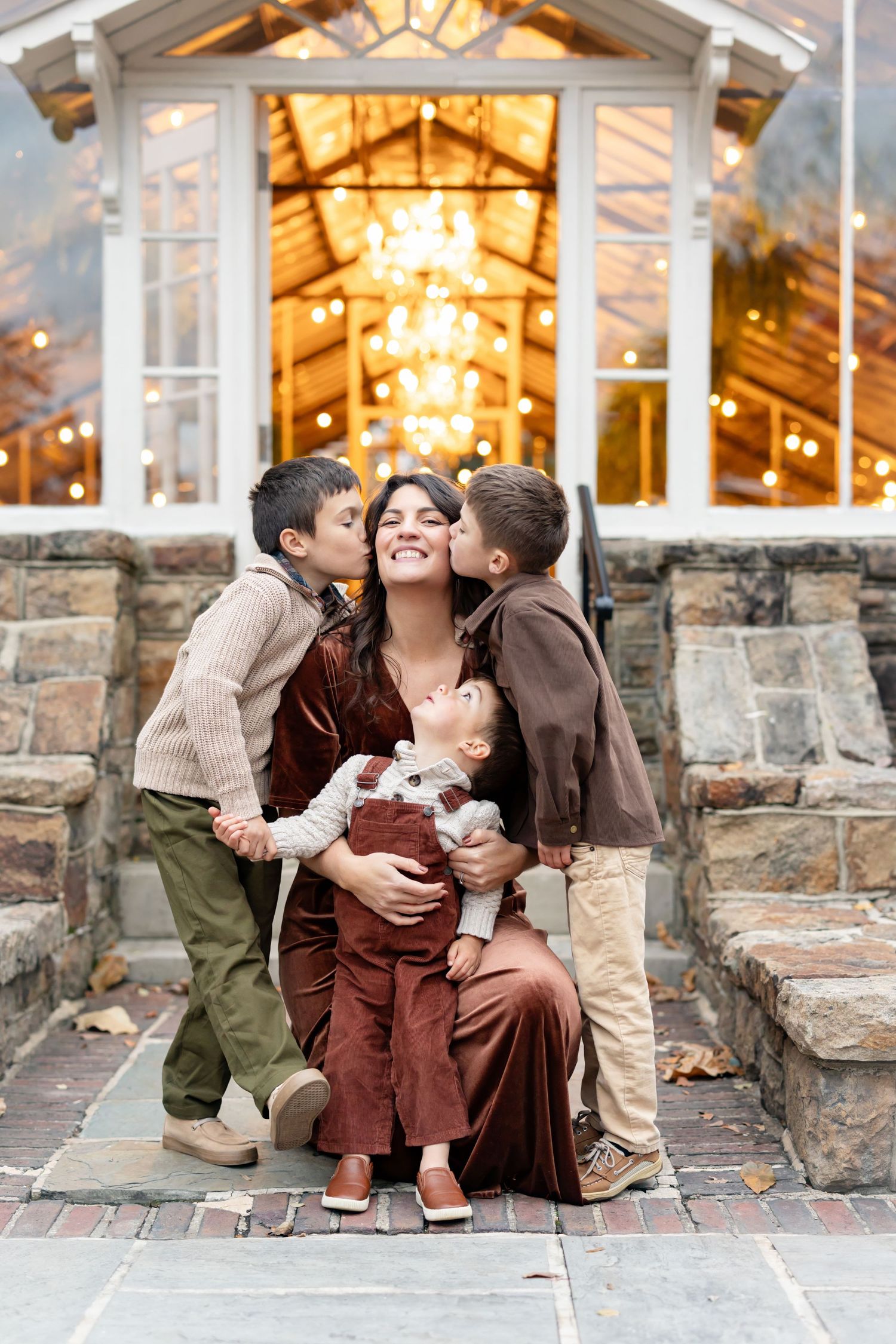 A family shares tender moments together while sitting on stone steps at a rustic venue with warm lighting.