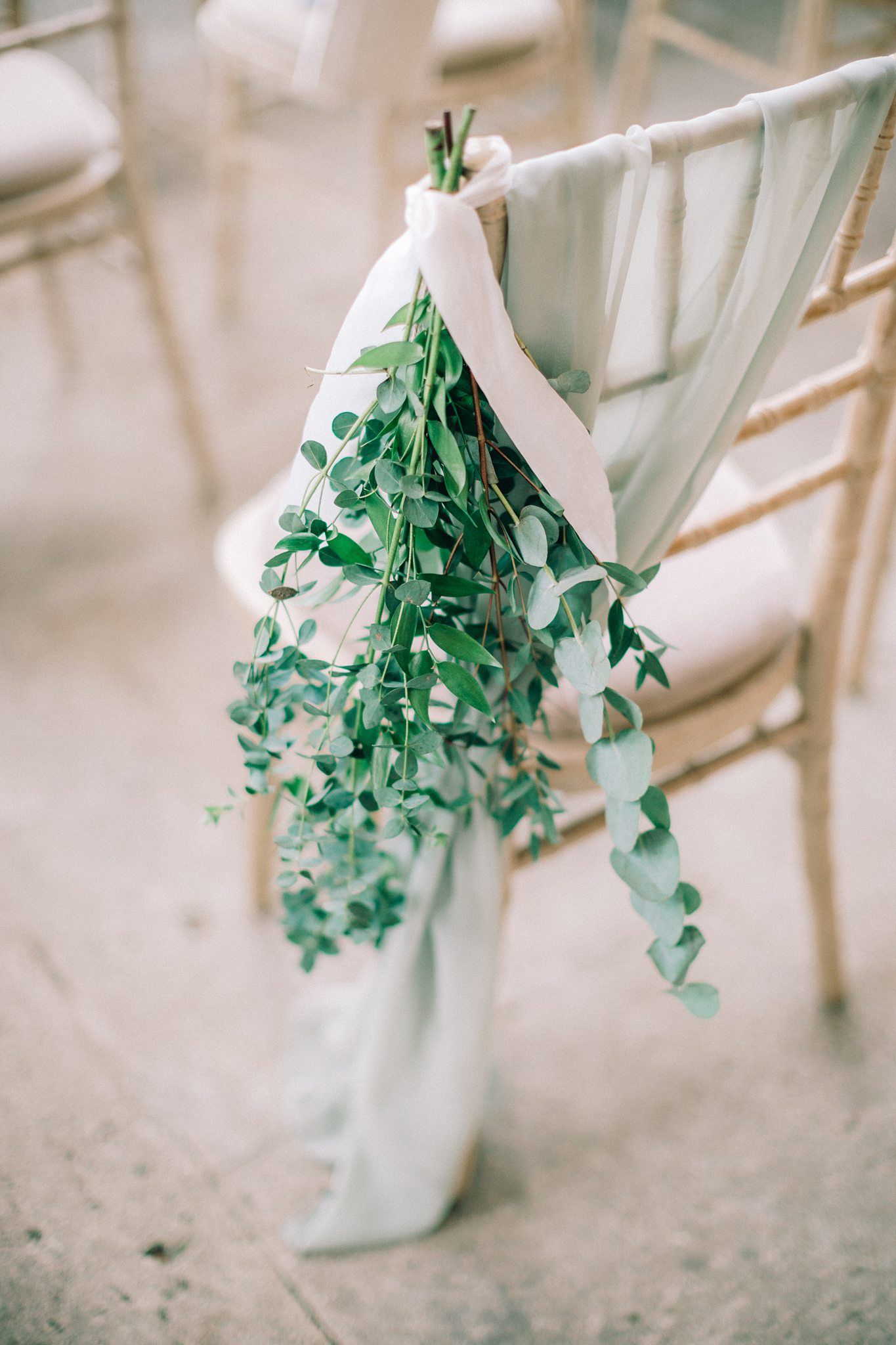 Fresh green eucalyptus branch tied on a white chair at a wedding ceremony at Lunenberg wedding venue the Farm at South Cove.