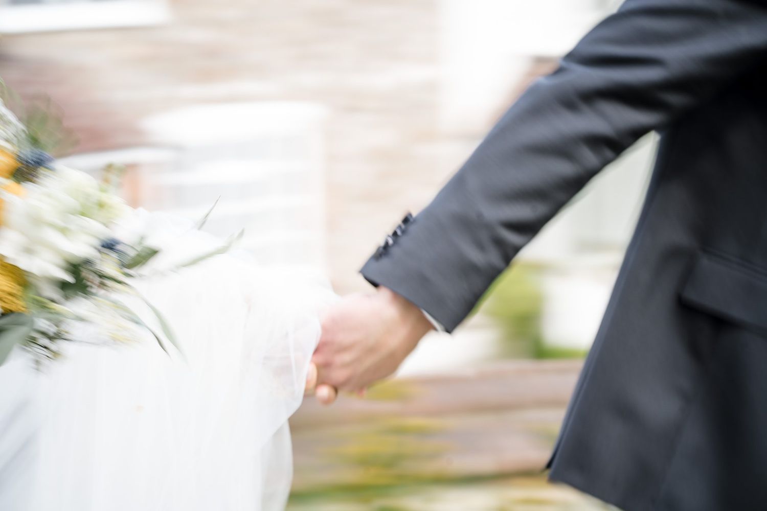 Close-up motion blur of couple holding hands around the Farm at South Cove with bride in white dress and groom in dark suit together.