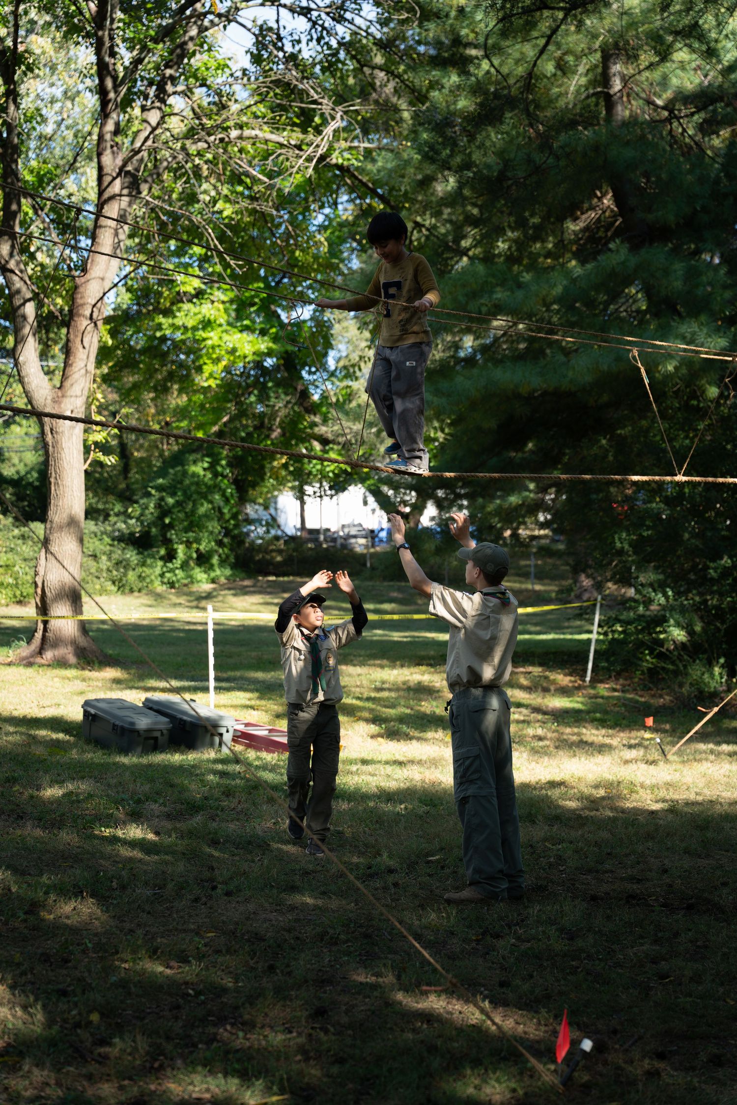 People playing outdoor games in a wooded park area on a sunny day.