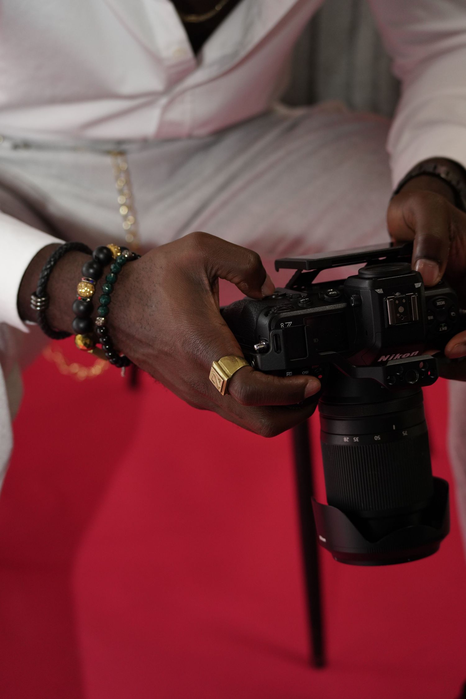 Close-up of hands holding a professional camera against a red background.