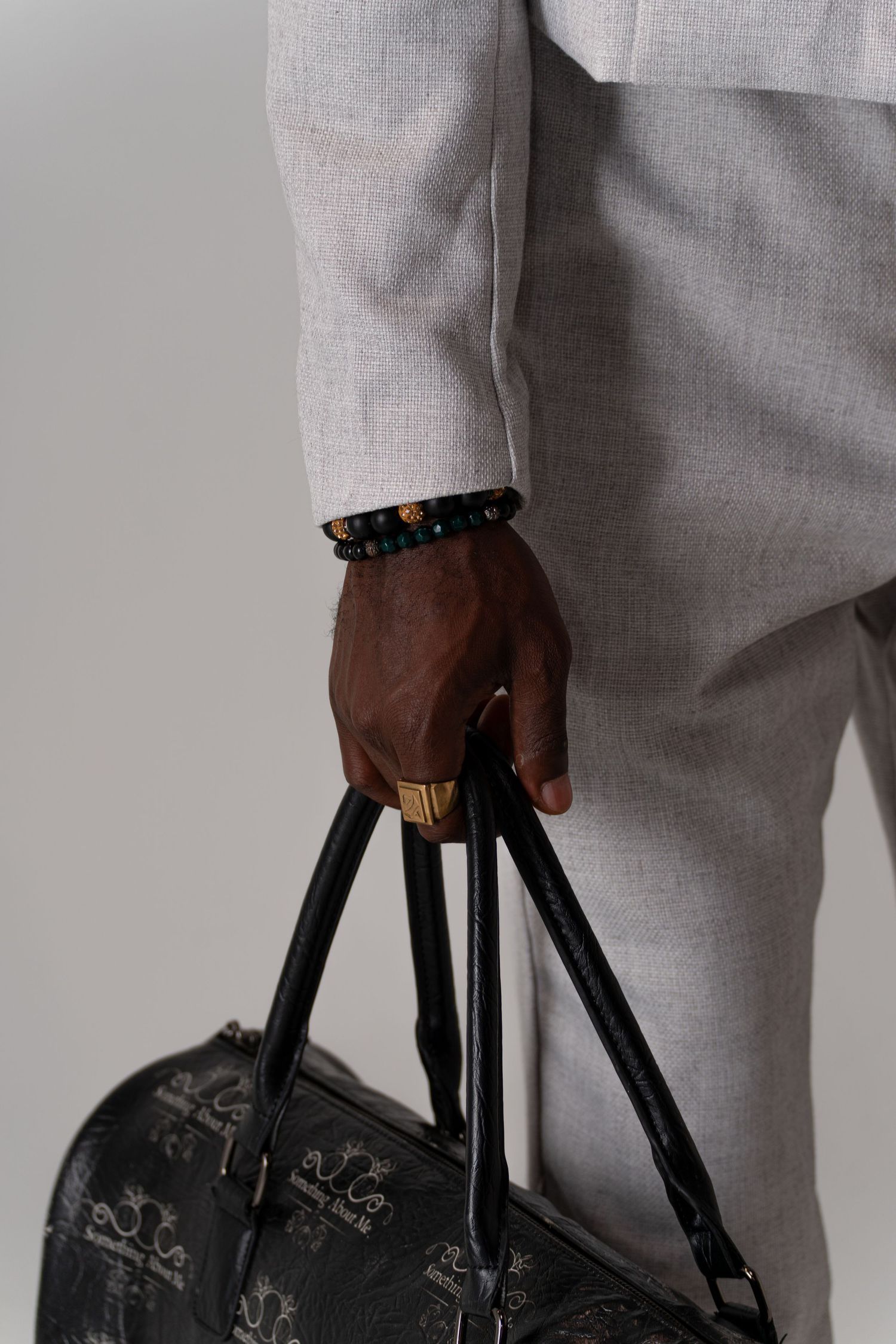 Close-up view of hands holding a black leather briefcase against a white suit background.