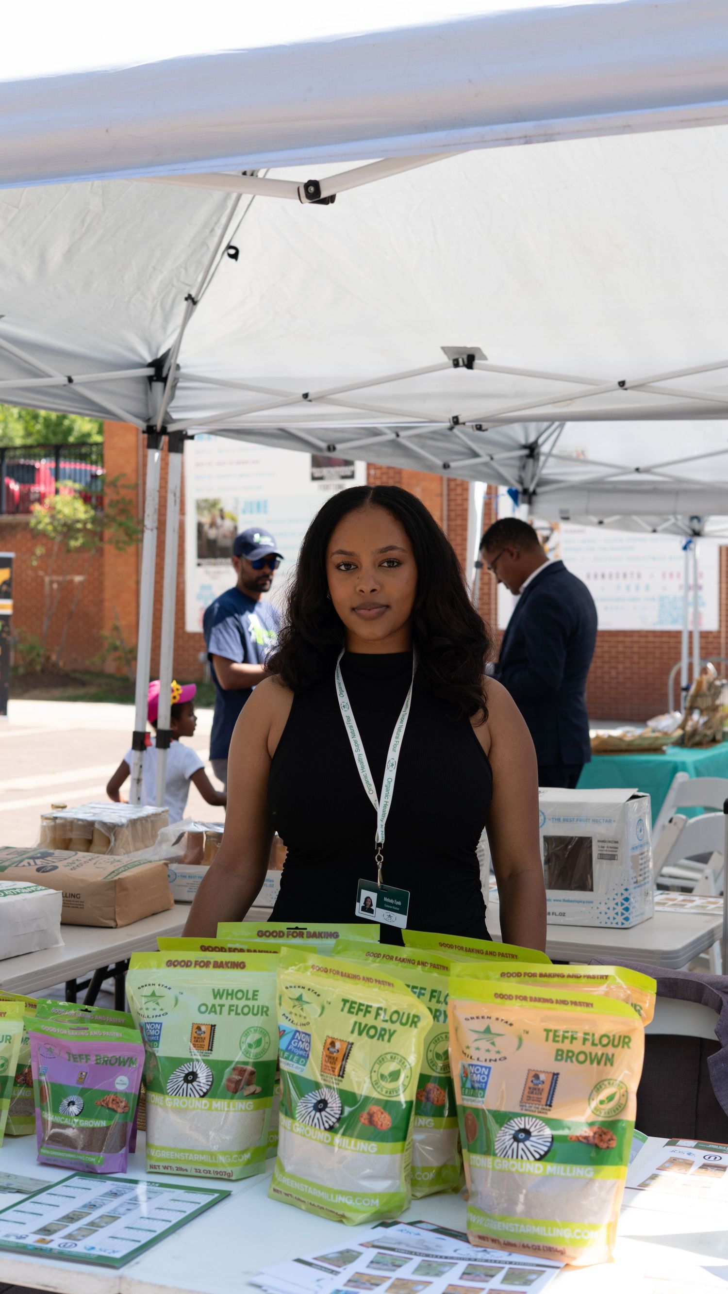 Vendor booth displaying various organic food products and snacks under white tent canopy.