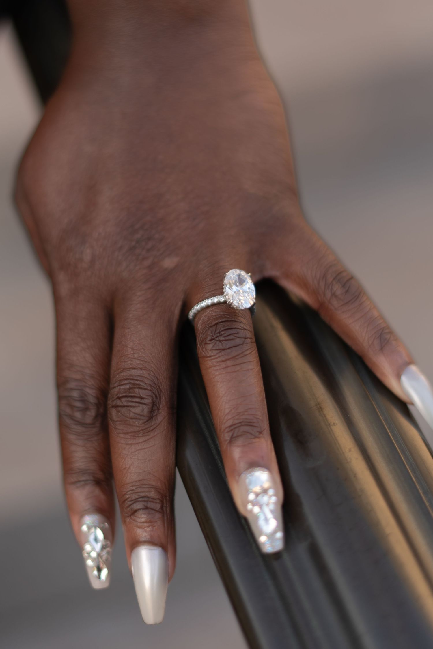 Close-up shots of elegantly manicured hands with white nail polish and diamond engagement ring.