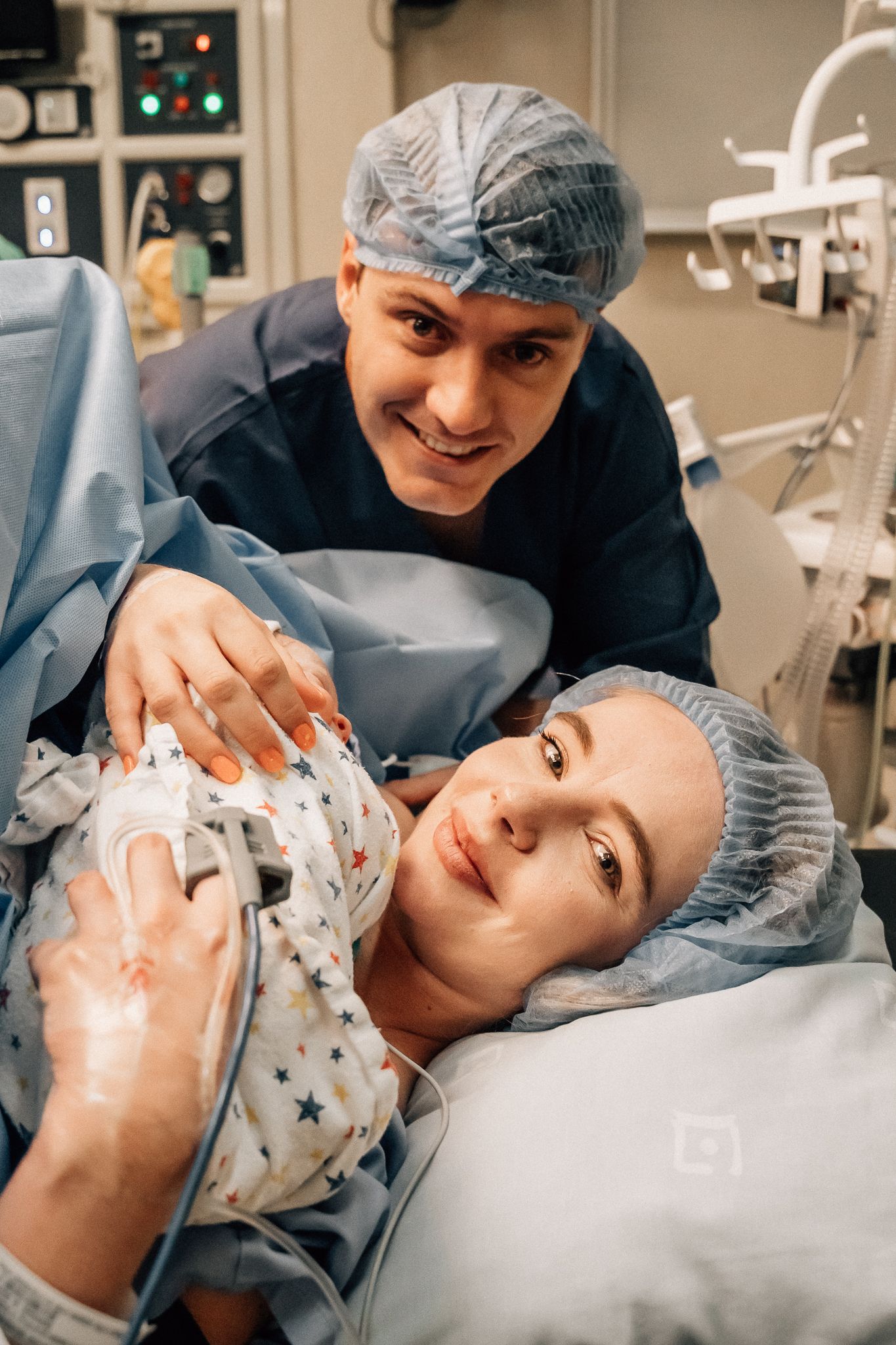 A heartwarming scene in a hospital room as parents welcome their newborn baby swaddled in a star-print blanket.