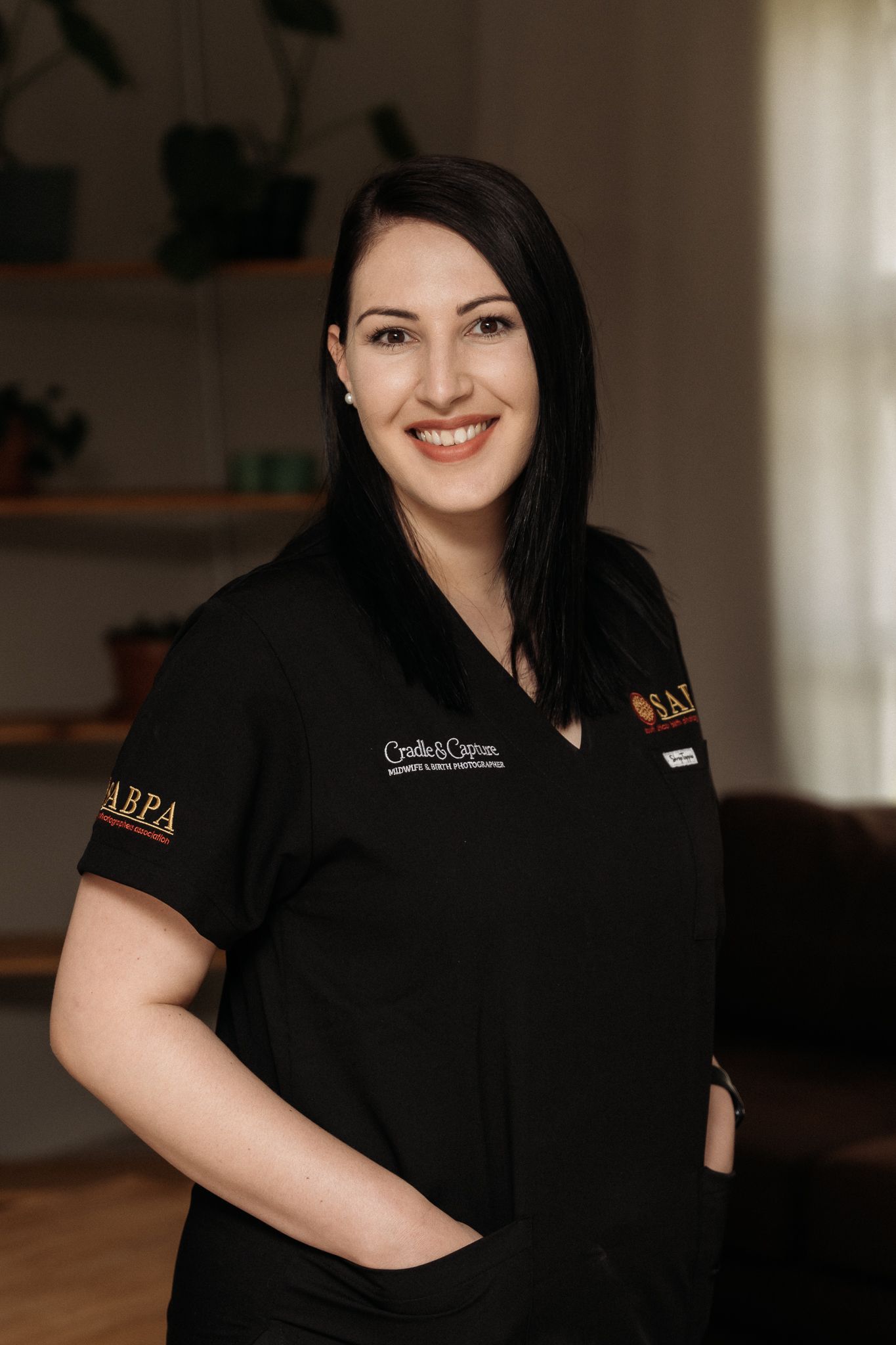 Professional headshot of a staff member wearing a black uniform with embroidered company logo.