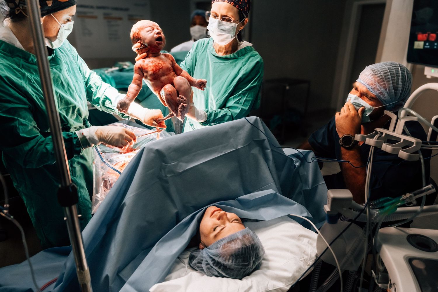 Medical team in surgical scrubs and masks performing an operation in a hospital operating room.