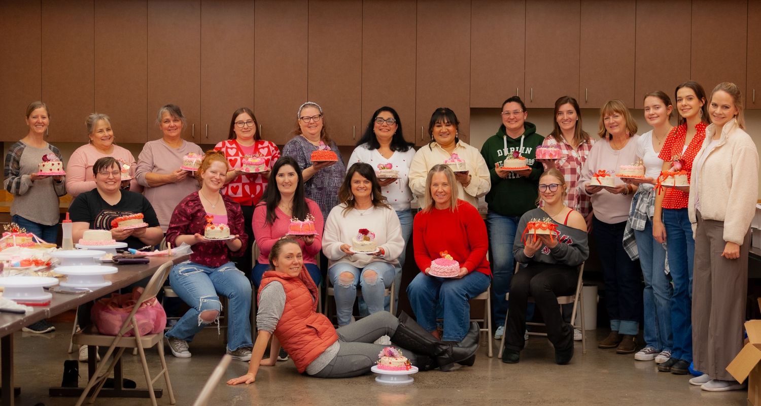 Group photo of participants holding decorated cakes at the sold-out cake decorating class in Moscow, Idaho, put on by La Pâtissière.