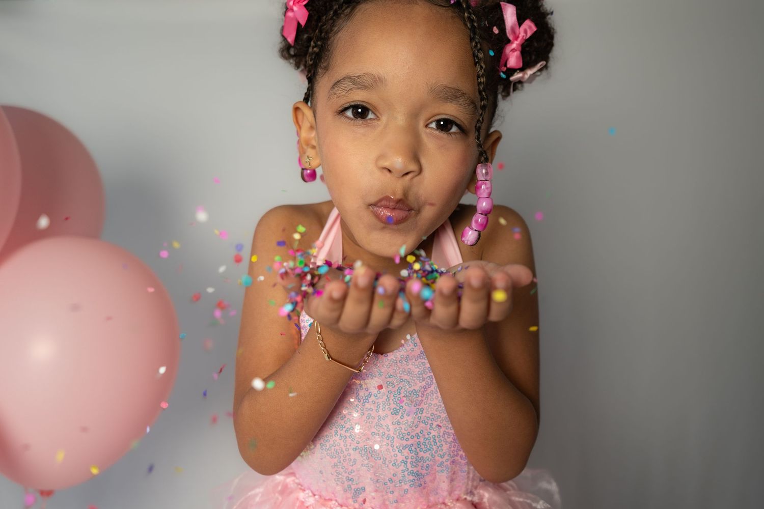 Pink confetti and glitter create a magical celebratory mood in a soft-toned photoshoot.