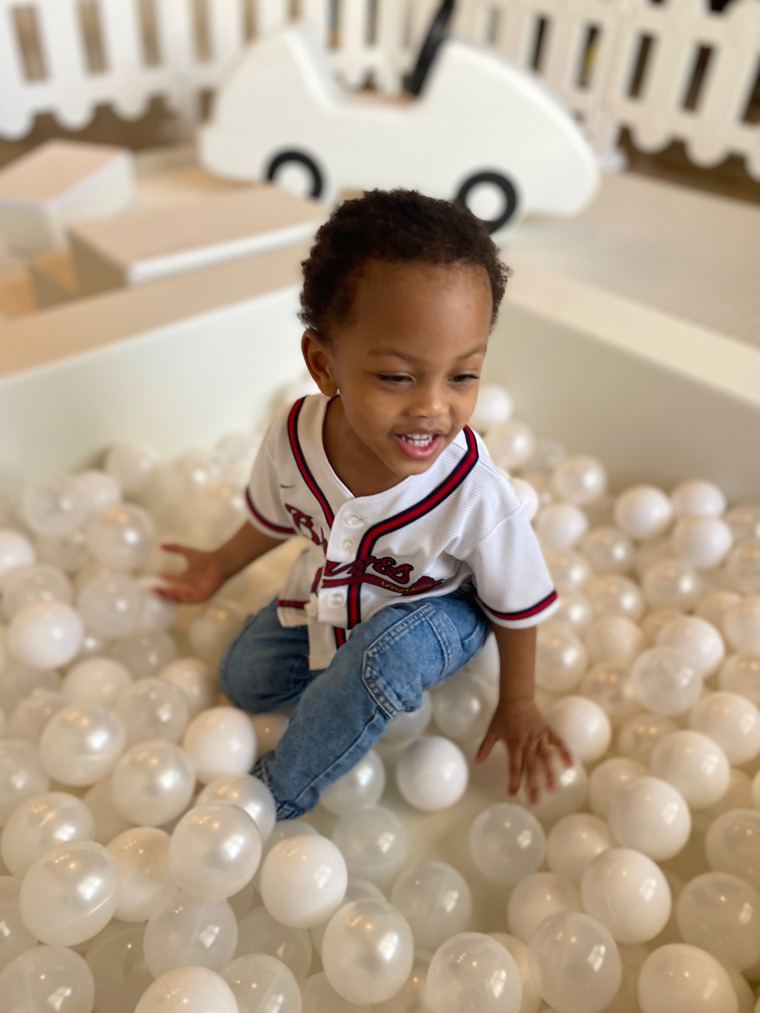 Ball pit filled with white spheres in a playroom setting.