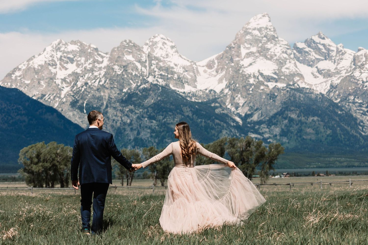 Two people celebrate their wedding day against the majestic backdrop of snow-capped Grand Teton mountains.