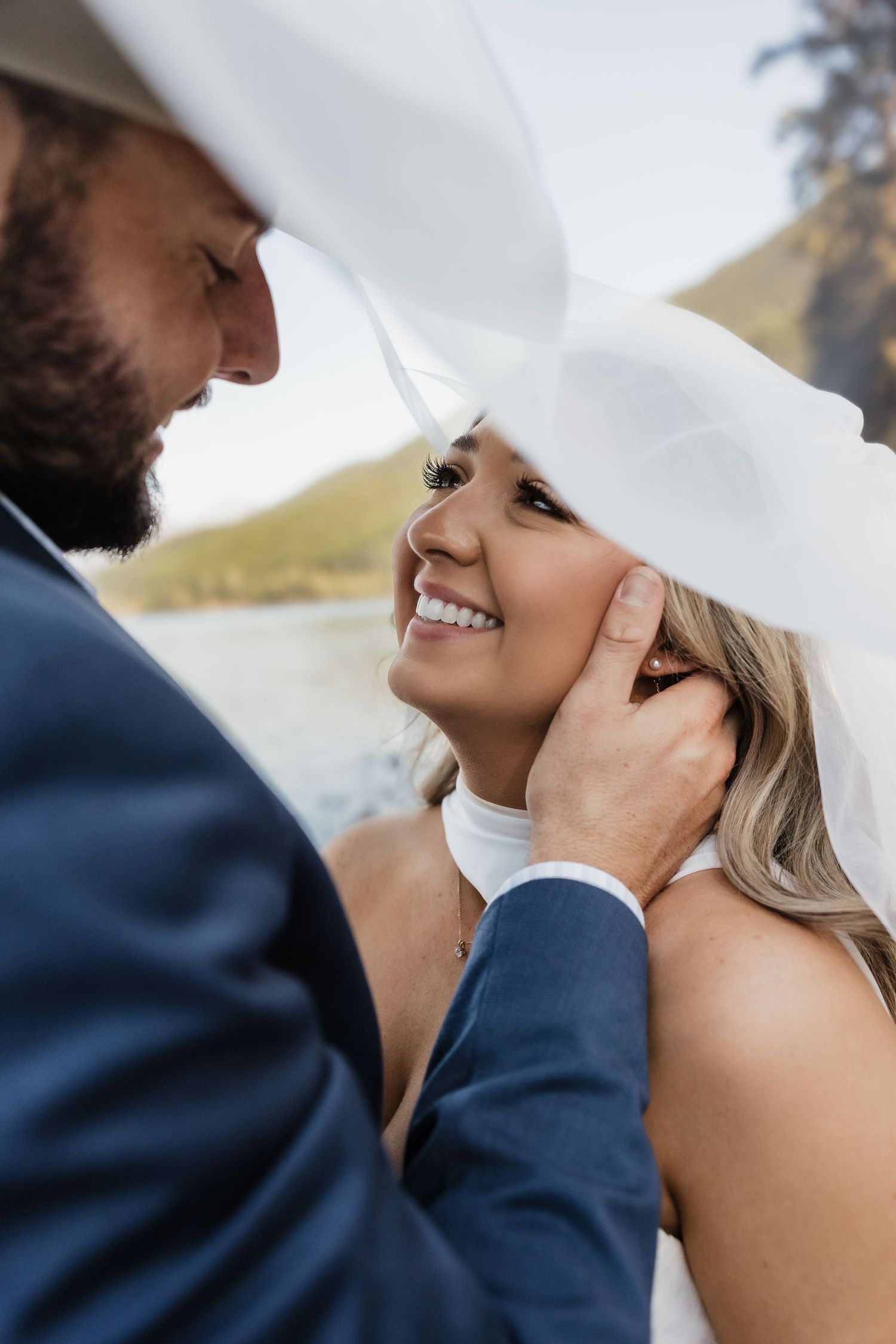 Romantic wedding couple sharing an intimate moment outdoors while wearing traditional wedding attire.